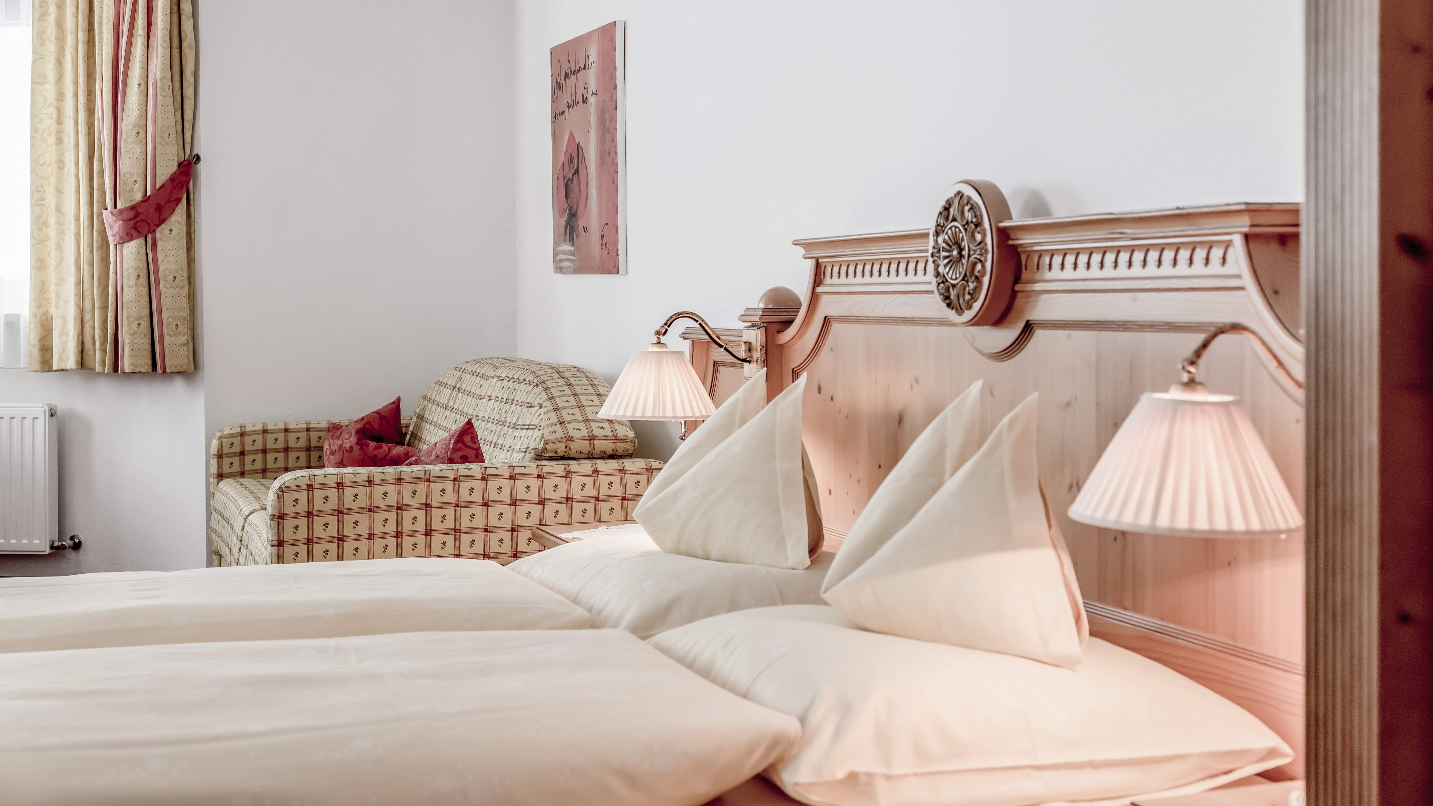 Elegantes Schlafzimmer im Alpenland Helles Hotelzimmer mit zwei Betten, dekorativen Kissen und einem gemütlichen Sofa.