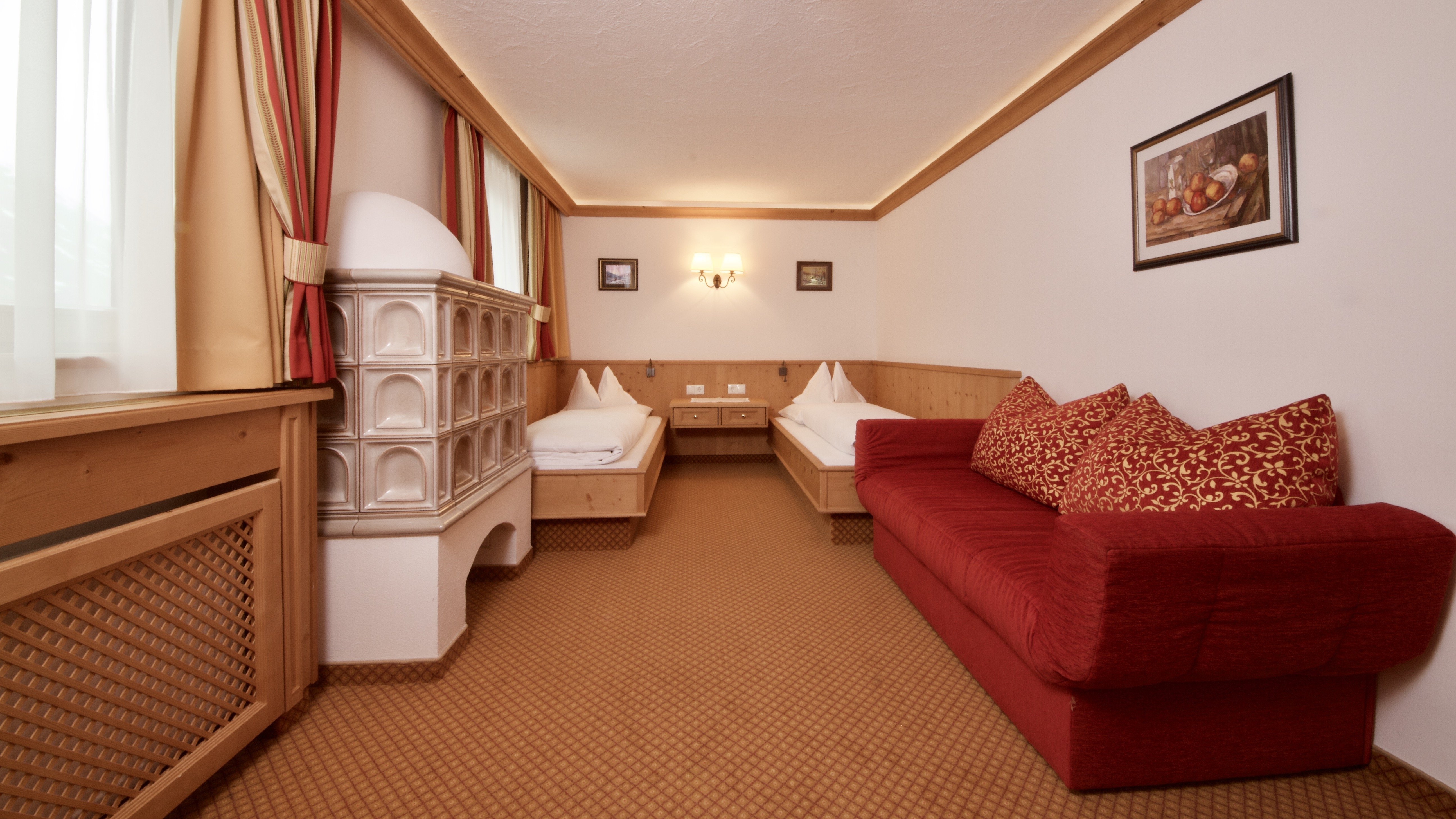 Helle Hotelzimmer mit traditionellem Flair Zwei Einzelbetten und ein rotes Sofa in einem Hotelzimmer mit Kachelofen und Dekorationen.
