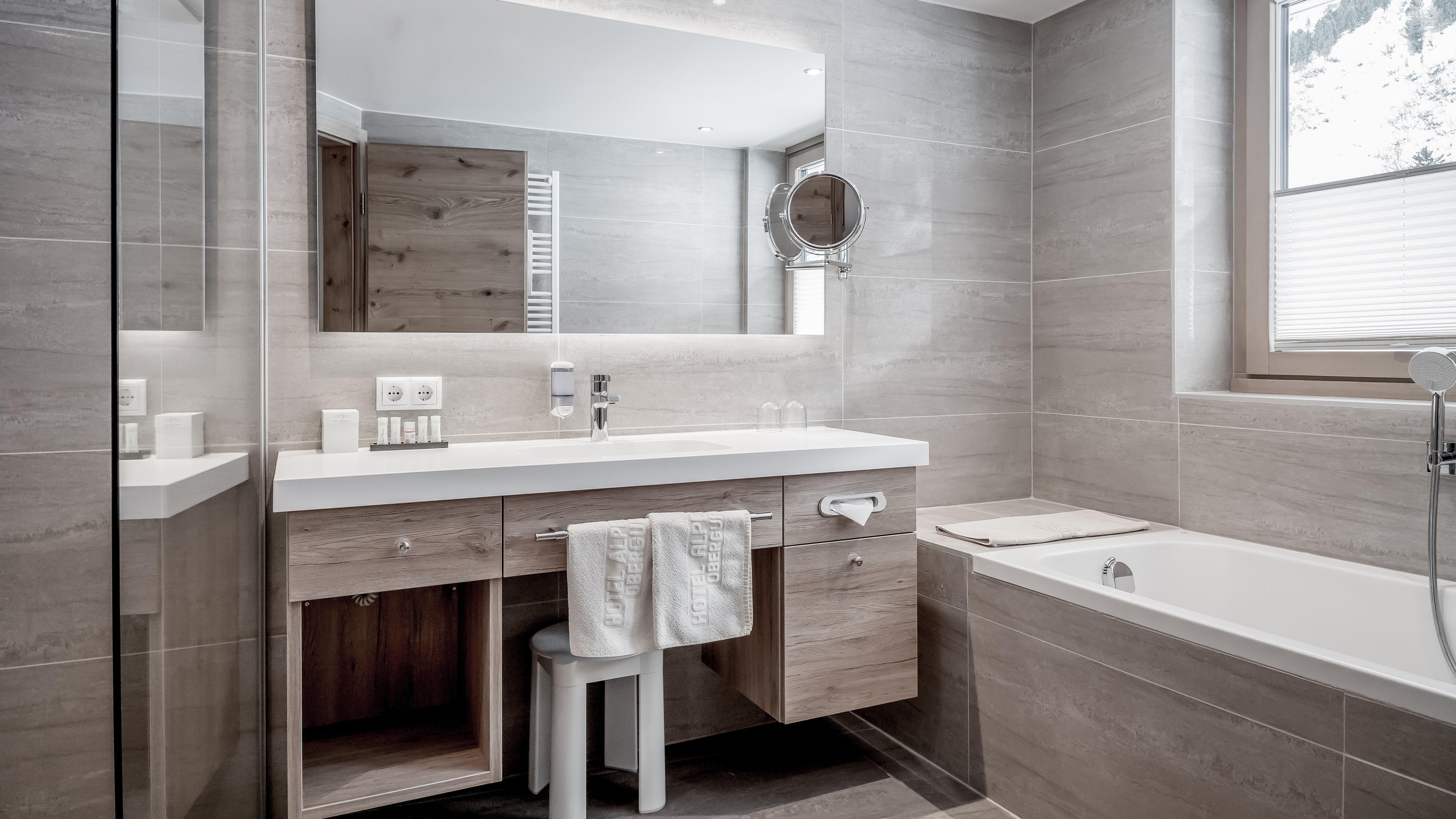 Modernes Bad für entspannte Momente Helles Badezimmer mit großem Spiegel, Holzwaschtisch und Badewanne im modernen Design