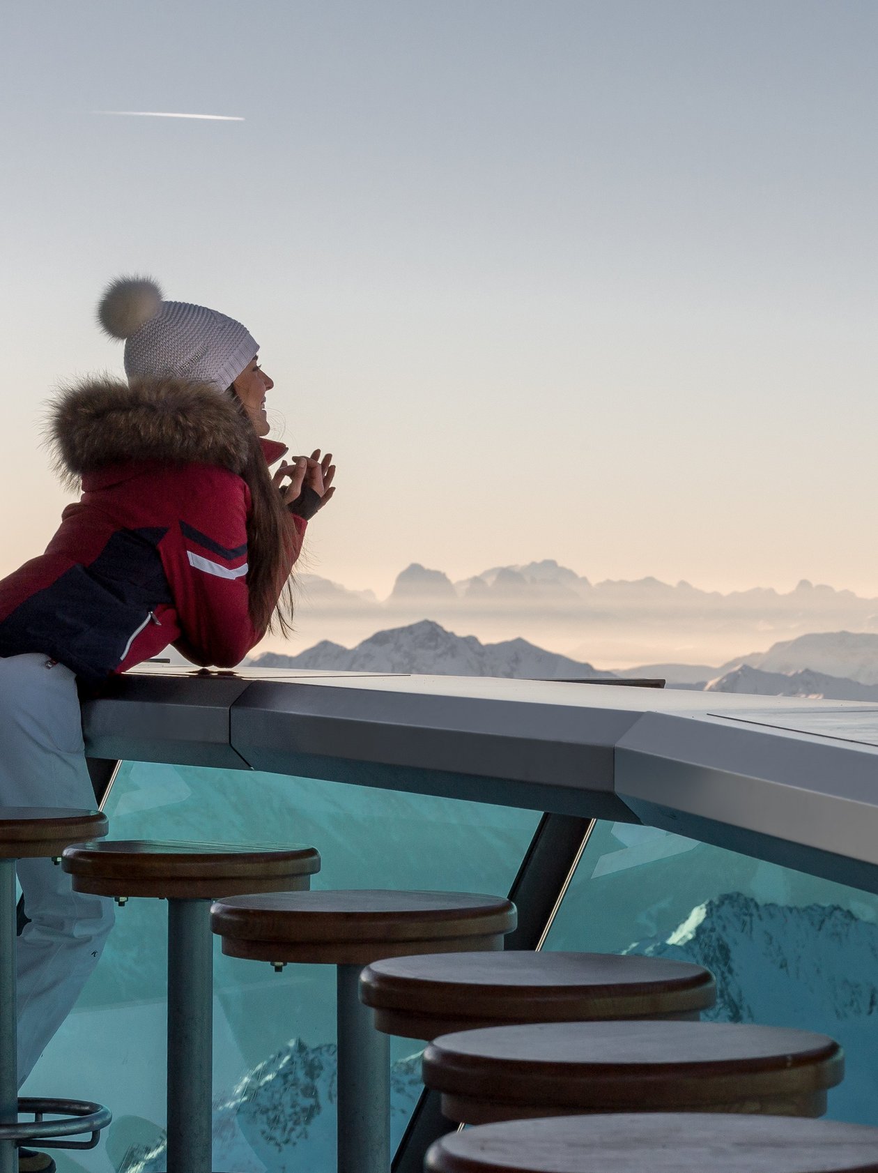 Panoramablick auf verschneite Berge Frau in Winterkleidung lehnt an einer Bar mit Blick auf schneebedeckte Berge im Skigebiet
