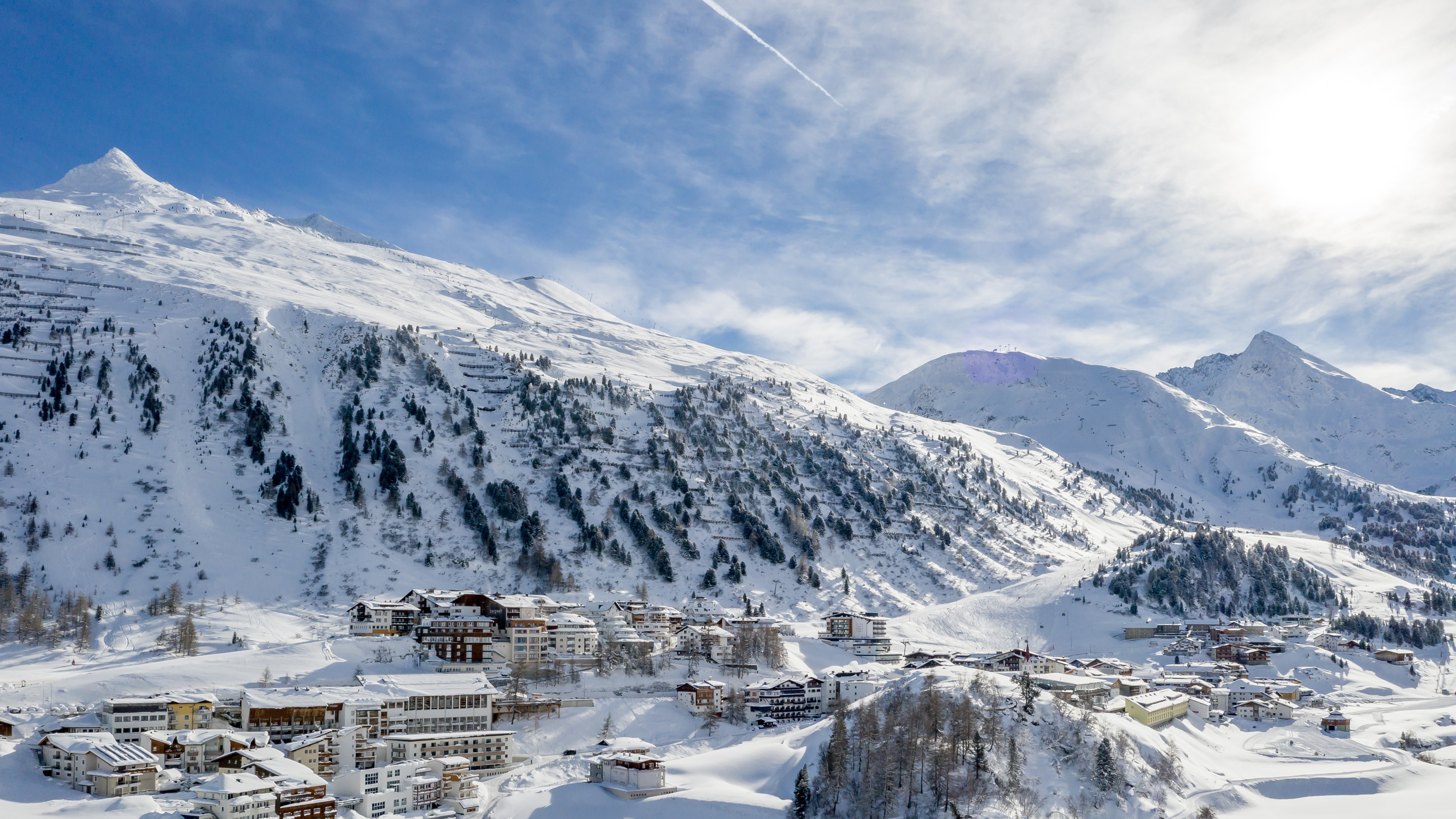 Verschneites Alpen-Dorf in einer beeindruckenden Winterlandschaft umgeben von hohen Bergen.