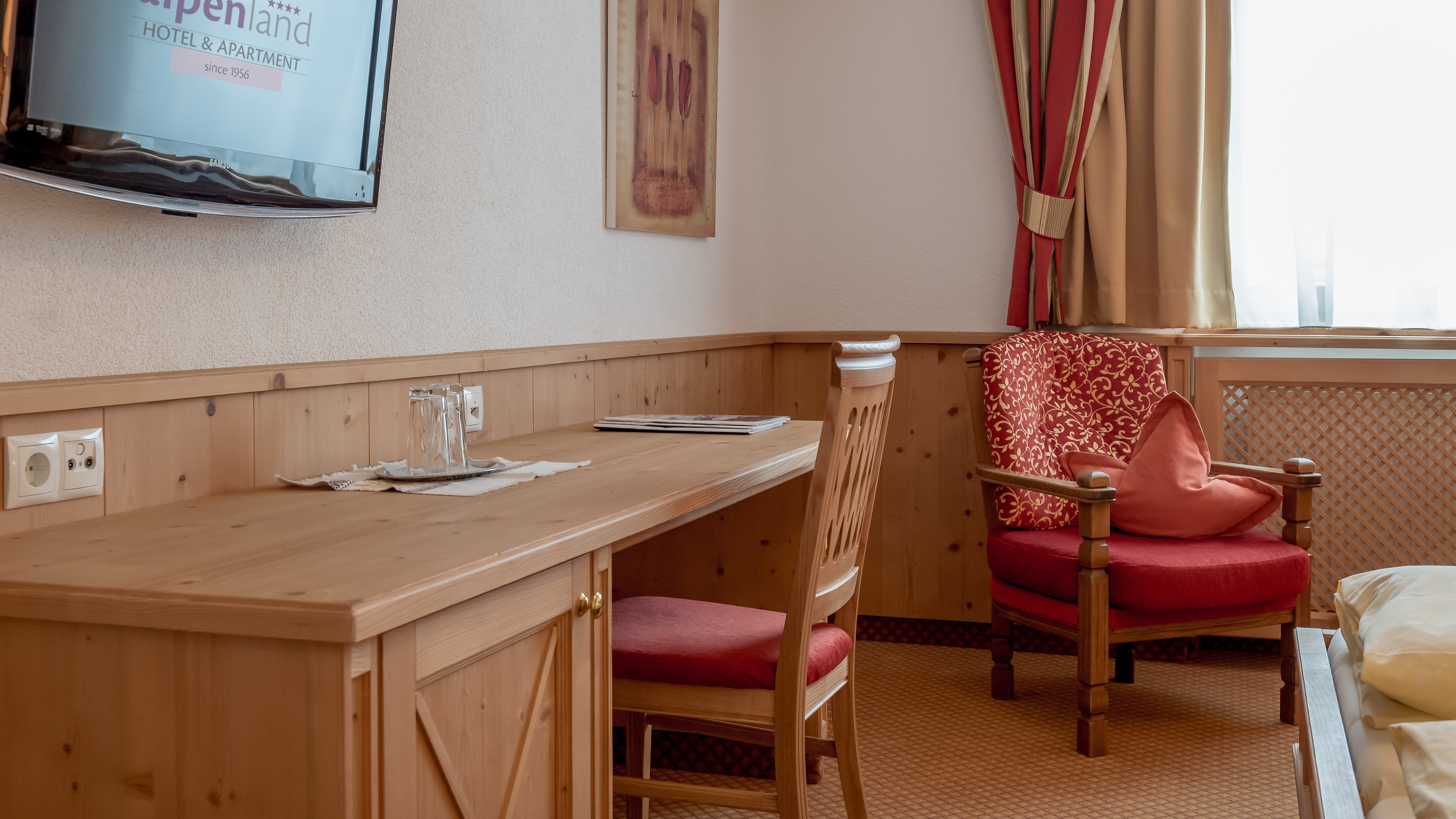 Moderne Hotelzimmergestaltung Hotelzimmer mit Schreibtisch, Stuhl und an der Wand montiertem Fernseher, sowie Dekoration und Fenster.