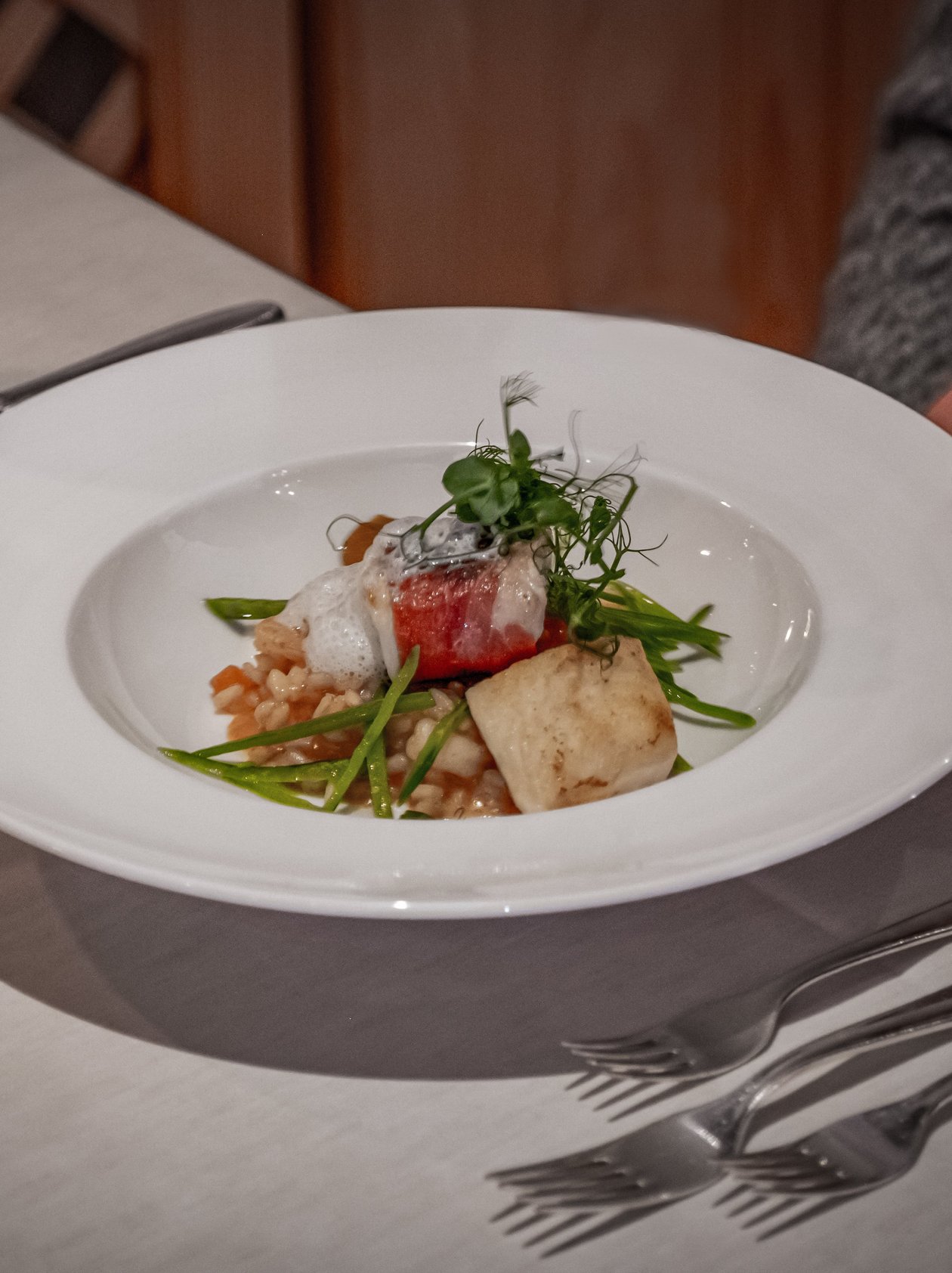 Gourmetgericht auf weißem Teller mit kreativen Zutaten und Garnierungen serviert.