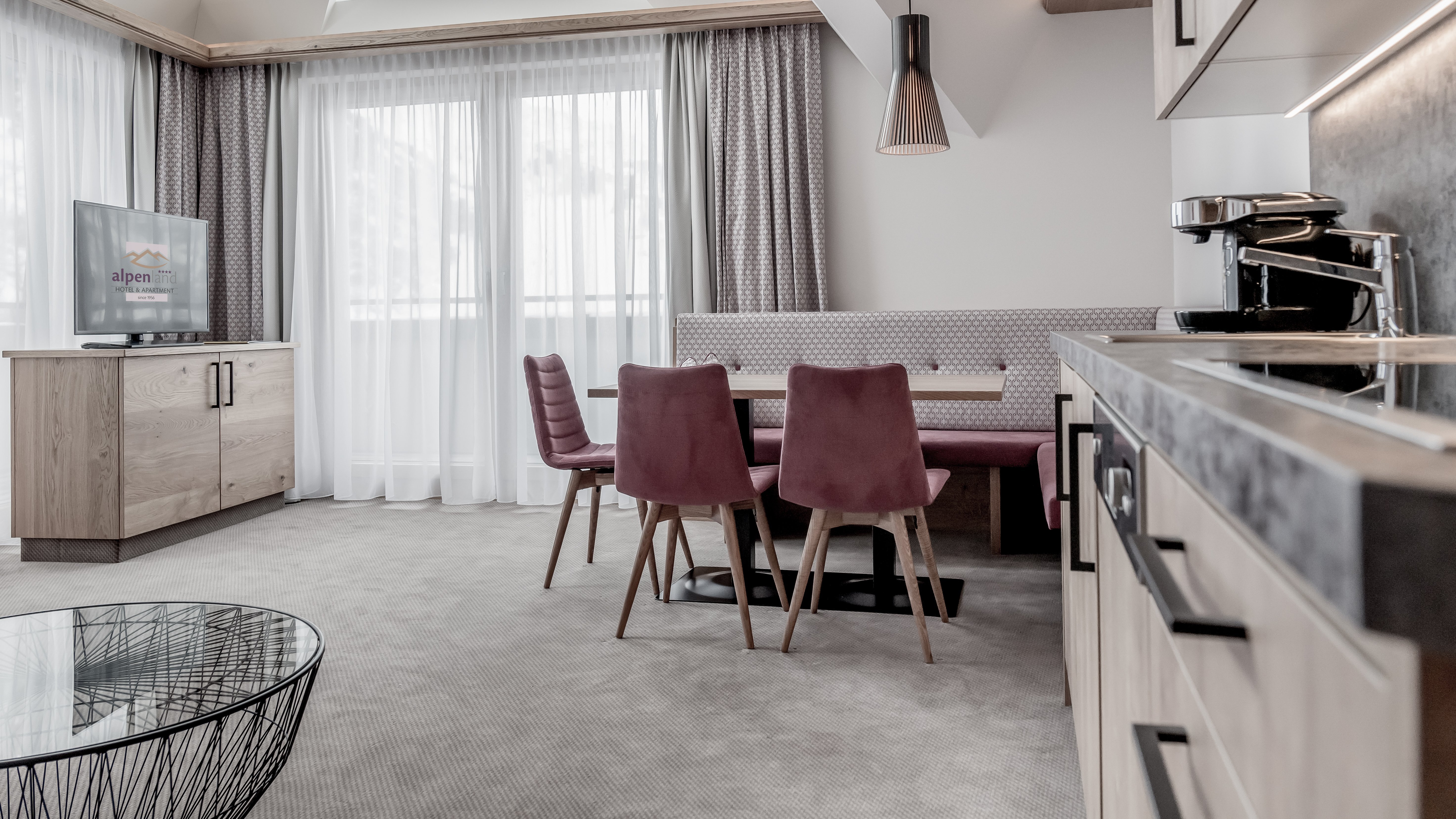 Moderne Hotel-Suite mit Essbereich Hotel-Suite mit Esstisch, Stühlen, Fernseher und Küchenzeile im Alpenland Hotel.