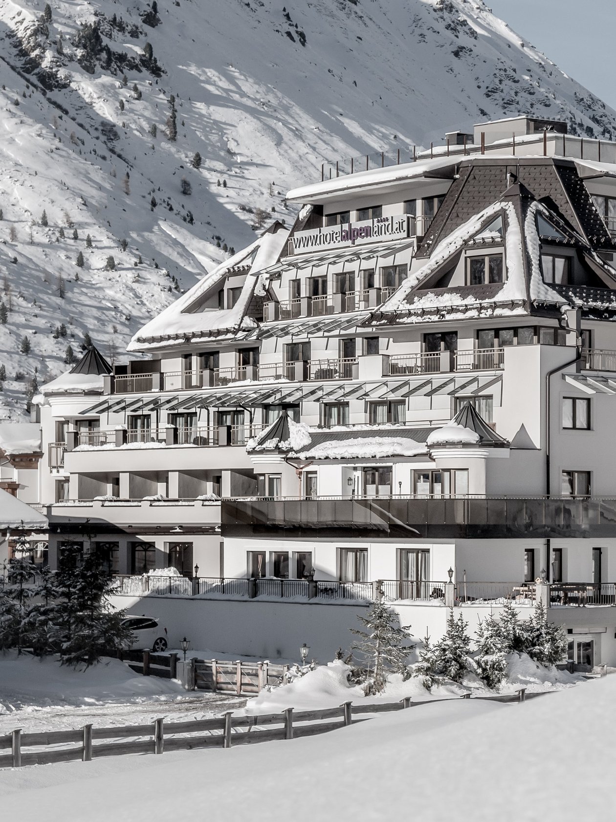 Großes Hotelgebäude in verschneiter Berglandschaft mit Balkonen und mehreren Etagen