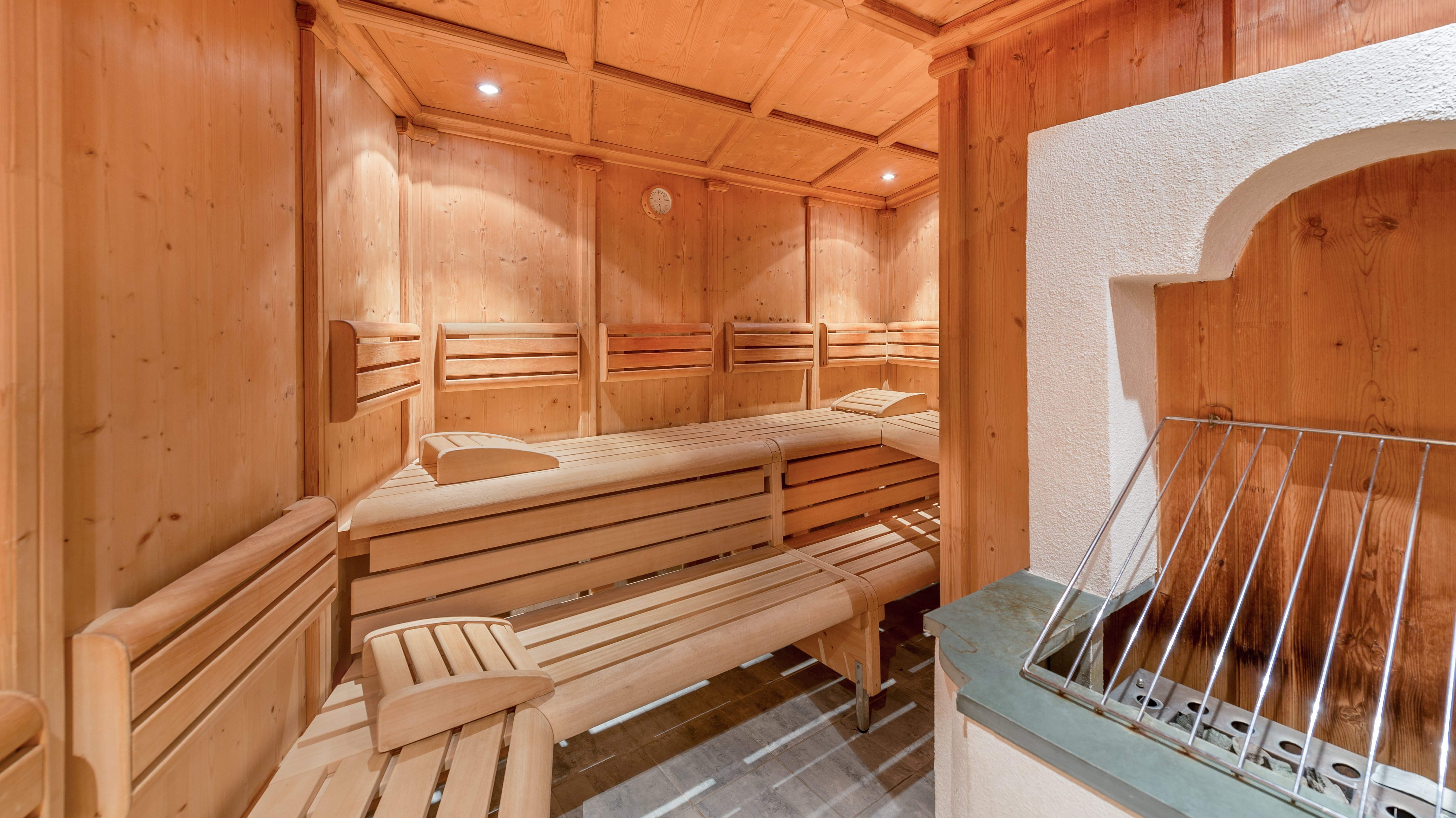 Innenansicht einer Holzsauna mit Bänken und einem Ofen zur Entspannung und Erholung.