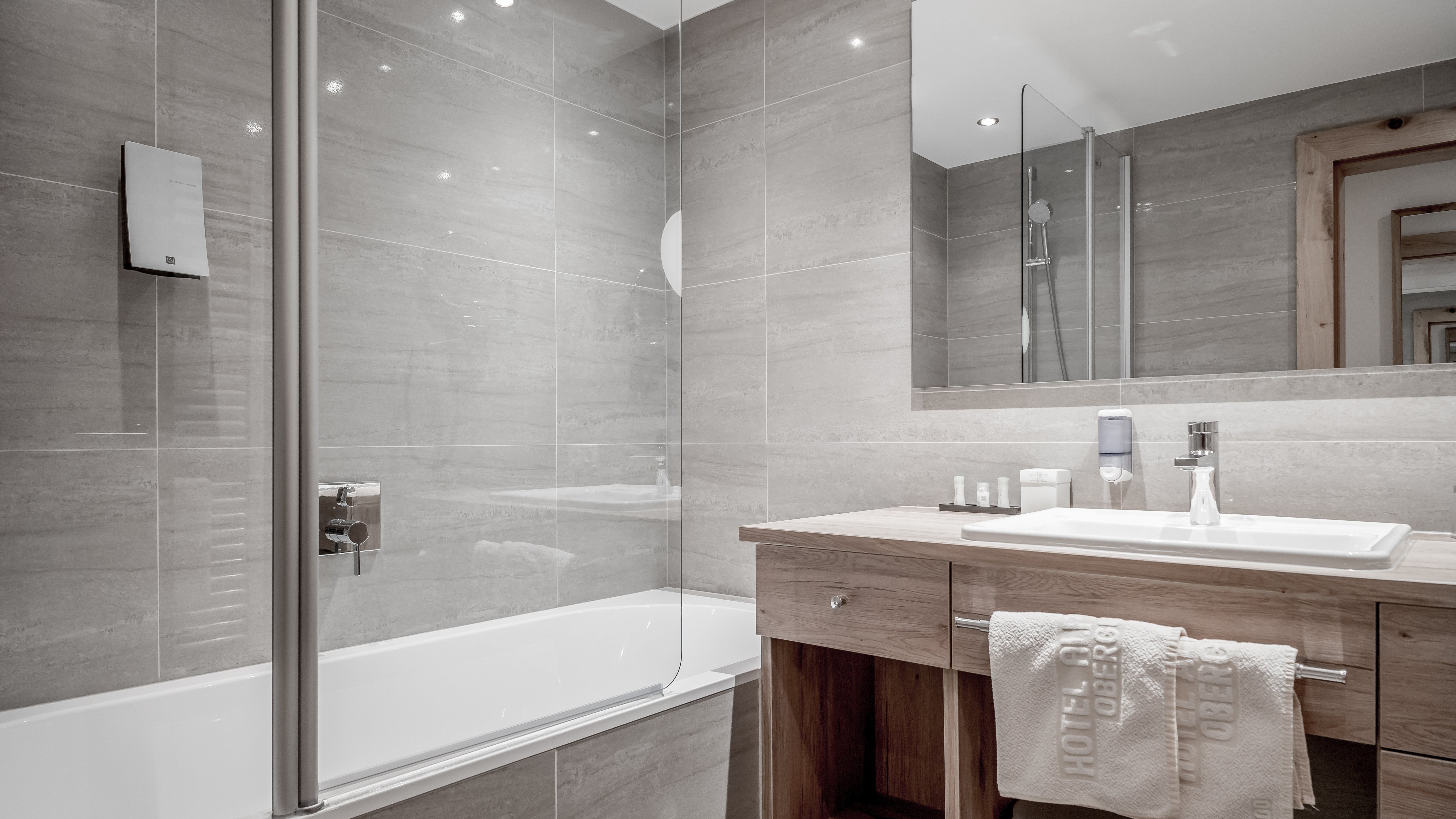 Elegantes Badezimmer im Alpenland Modernes Badezimmer mit freistehender Badewanne und Holzwaschtisch sowie großem Spiegel.