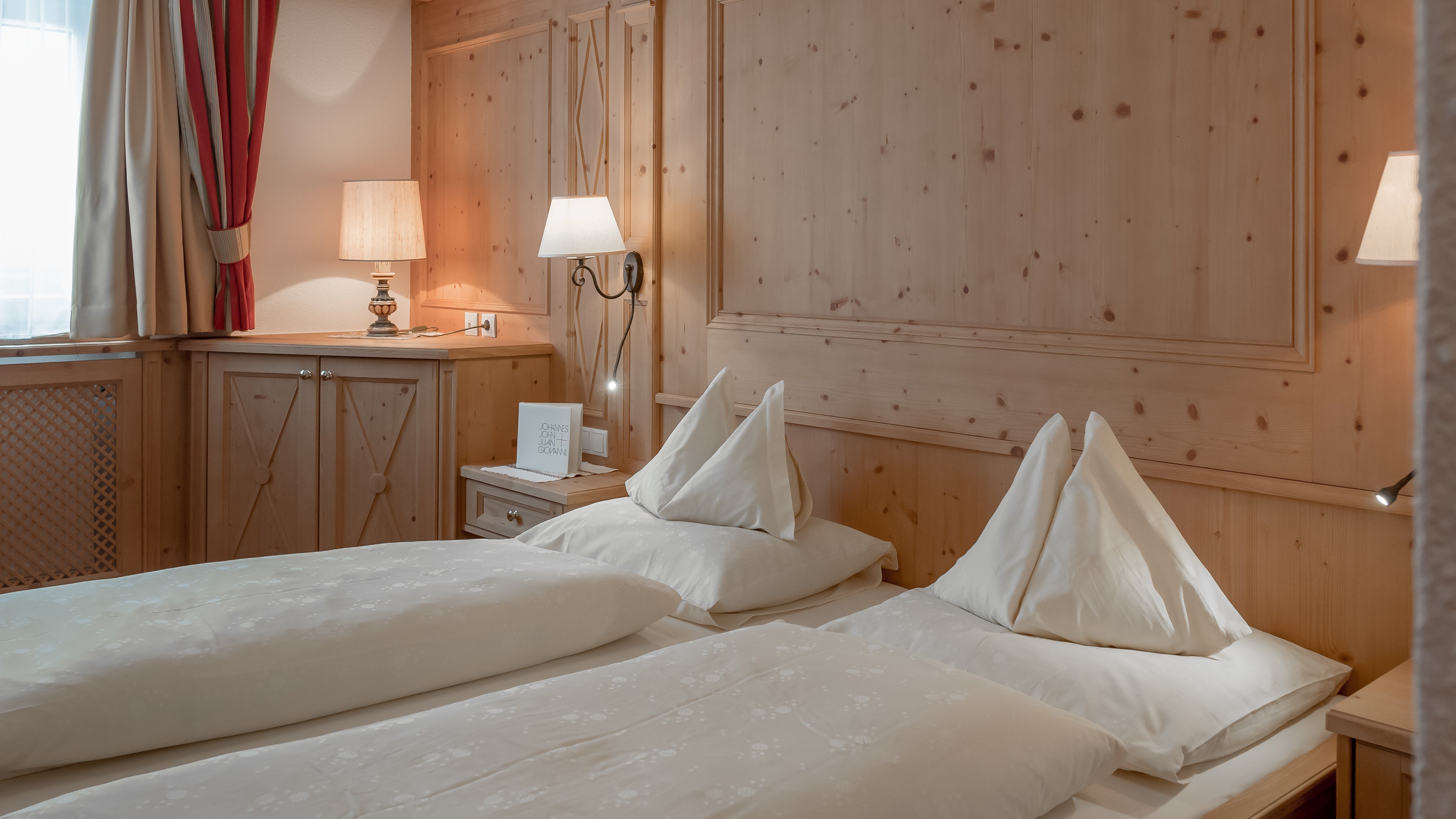 Gemütliche Unterkunft im Alpenland Helle Hotelzimmer mit zwei Betten, Holzverkleidung und warmem Licht für Behaglichkeit.