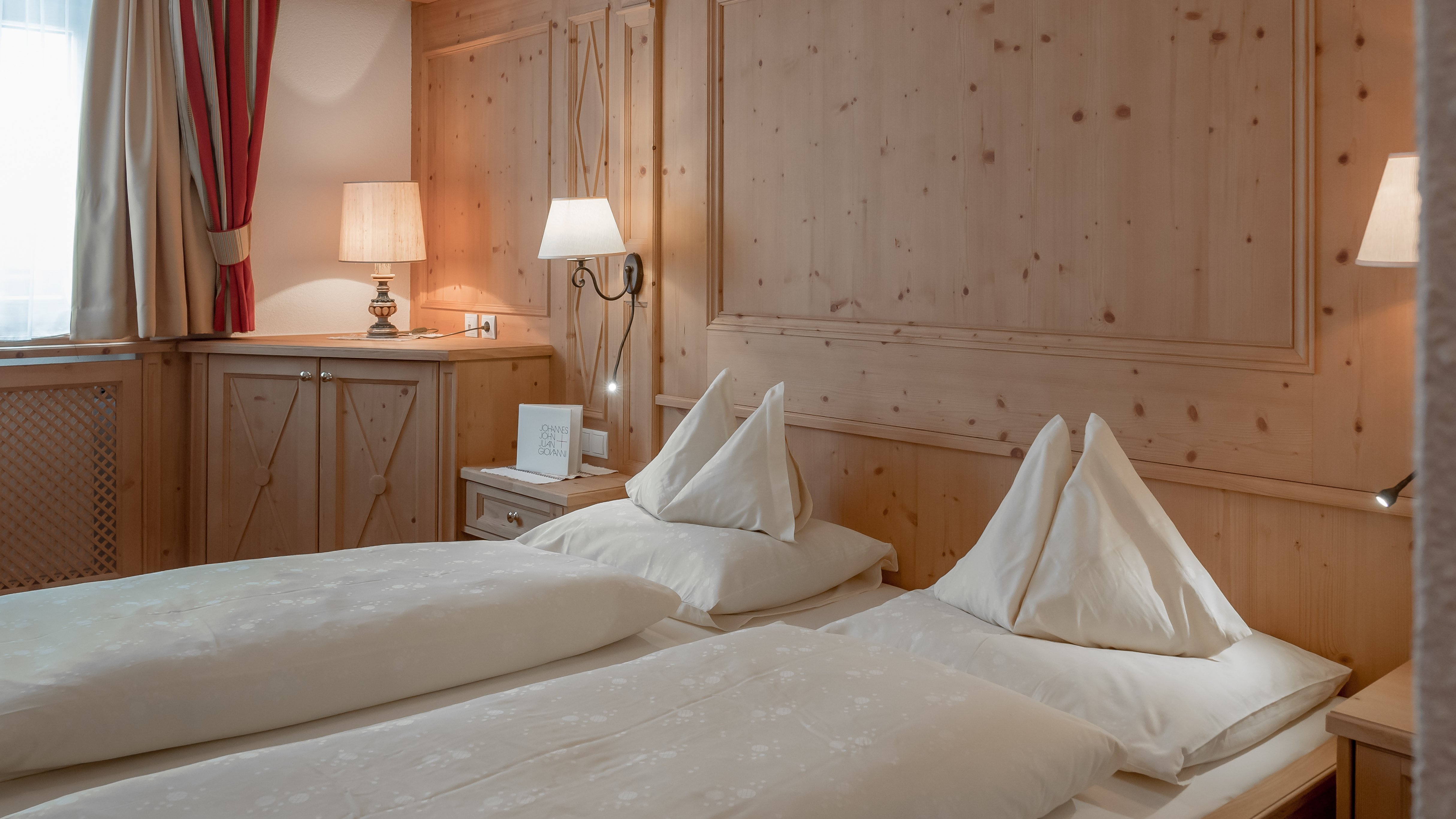 Gemütliche Unterkunft im Alpenland Helle Hotelzimmer mit zwei Betten, Holzverkleidung und warmem Licht für Behaglichkeit.
