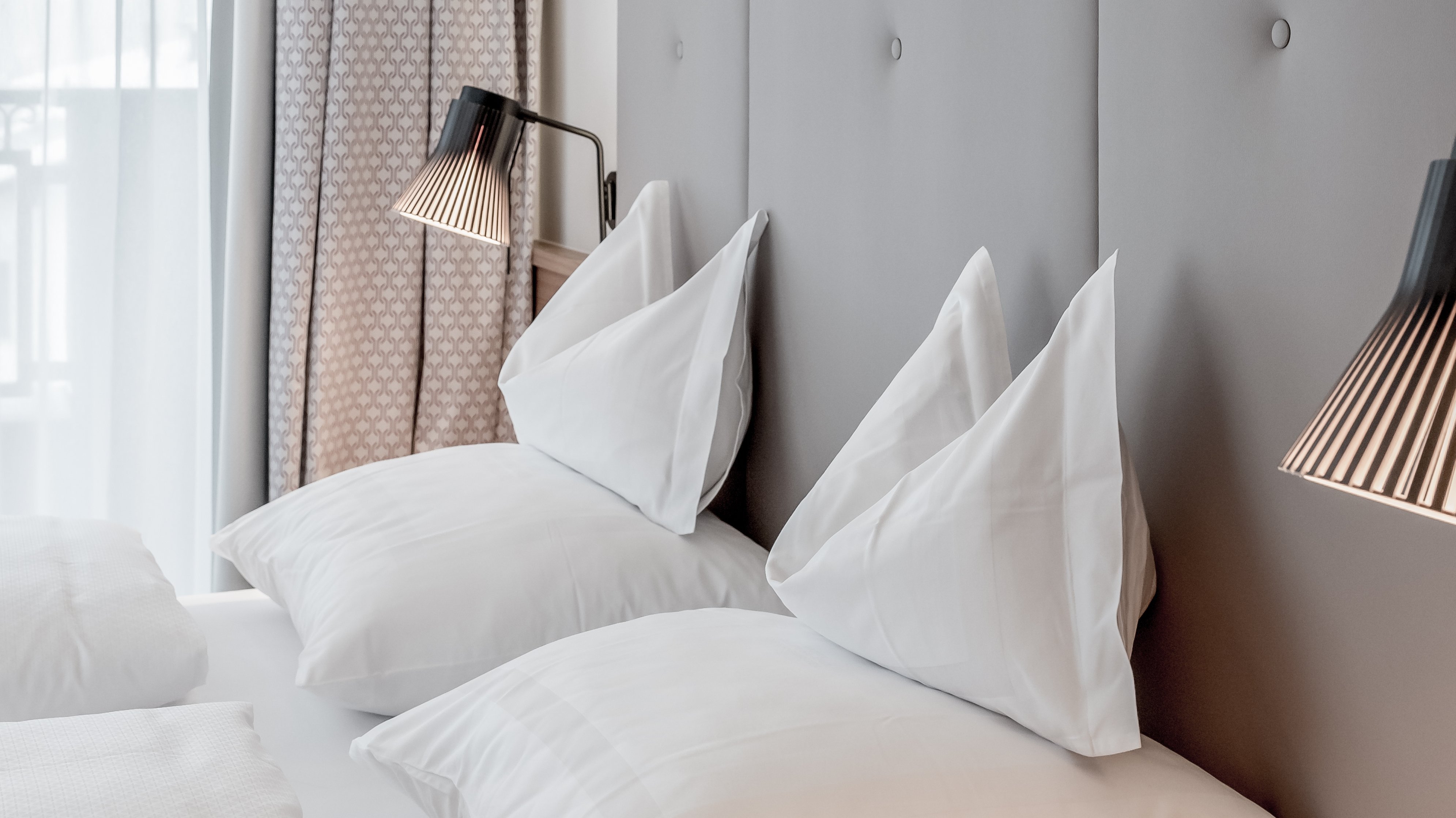 Modernes Schlafzimmer im Alpenland Schlafzimmer mit stilvollem Kopfteil, luxuriösen Bettwaren und modernen Lichtquellen.
