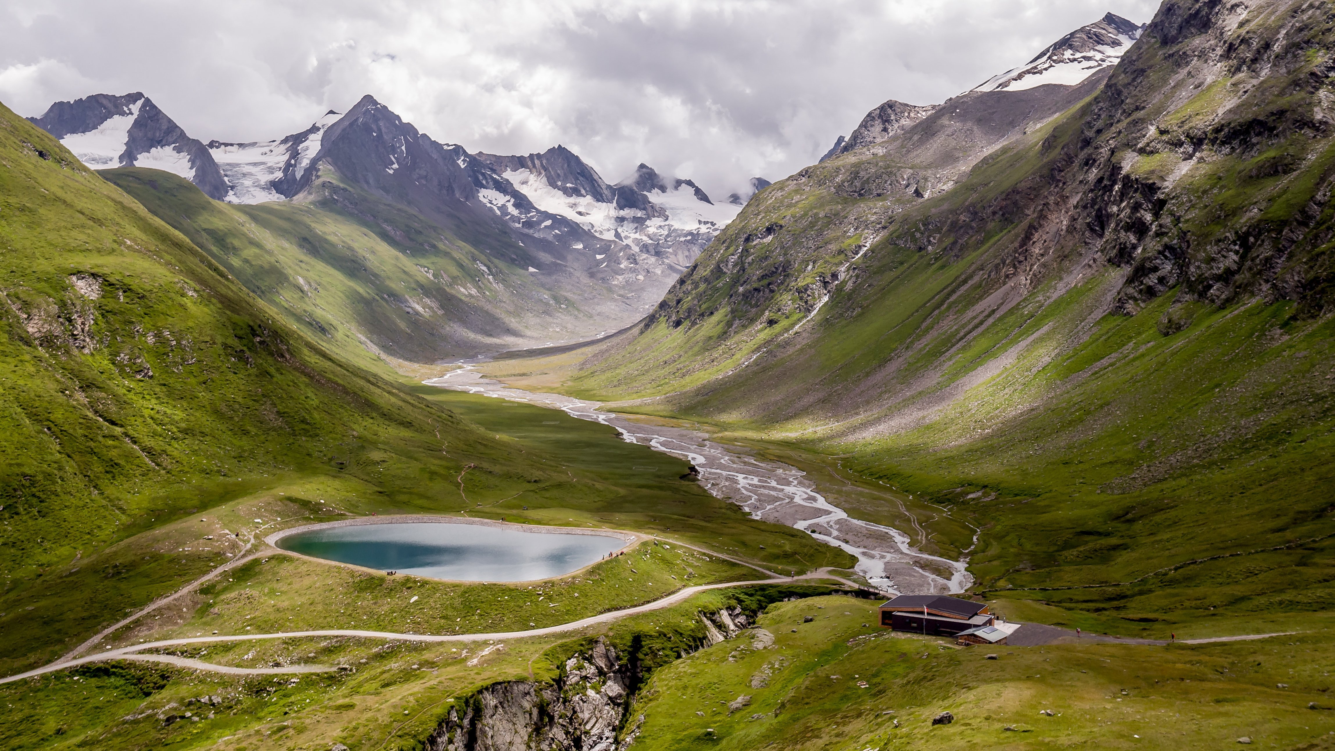Idyllische Berglandschaft mit Gletschersee Bergtal mit glitzerndem Gletschersee und schneebedeckten Gipfeln im Hintergrund.