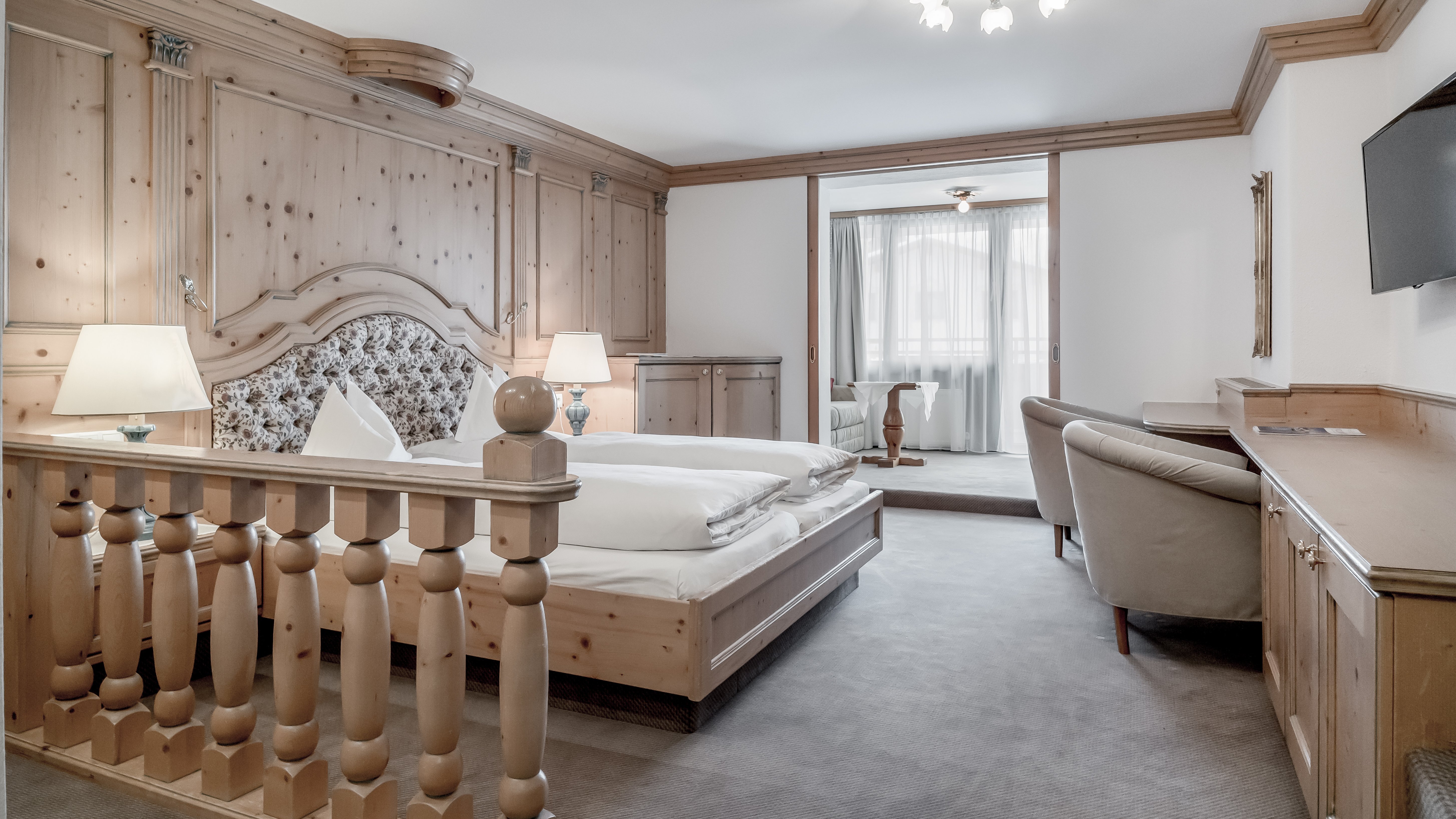 Luxuriöse Unterkunft im Alpenland Helles Schlafzimmer mit Holzverkleidung, großem Bett und modernen Annehmlichkeiten
