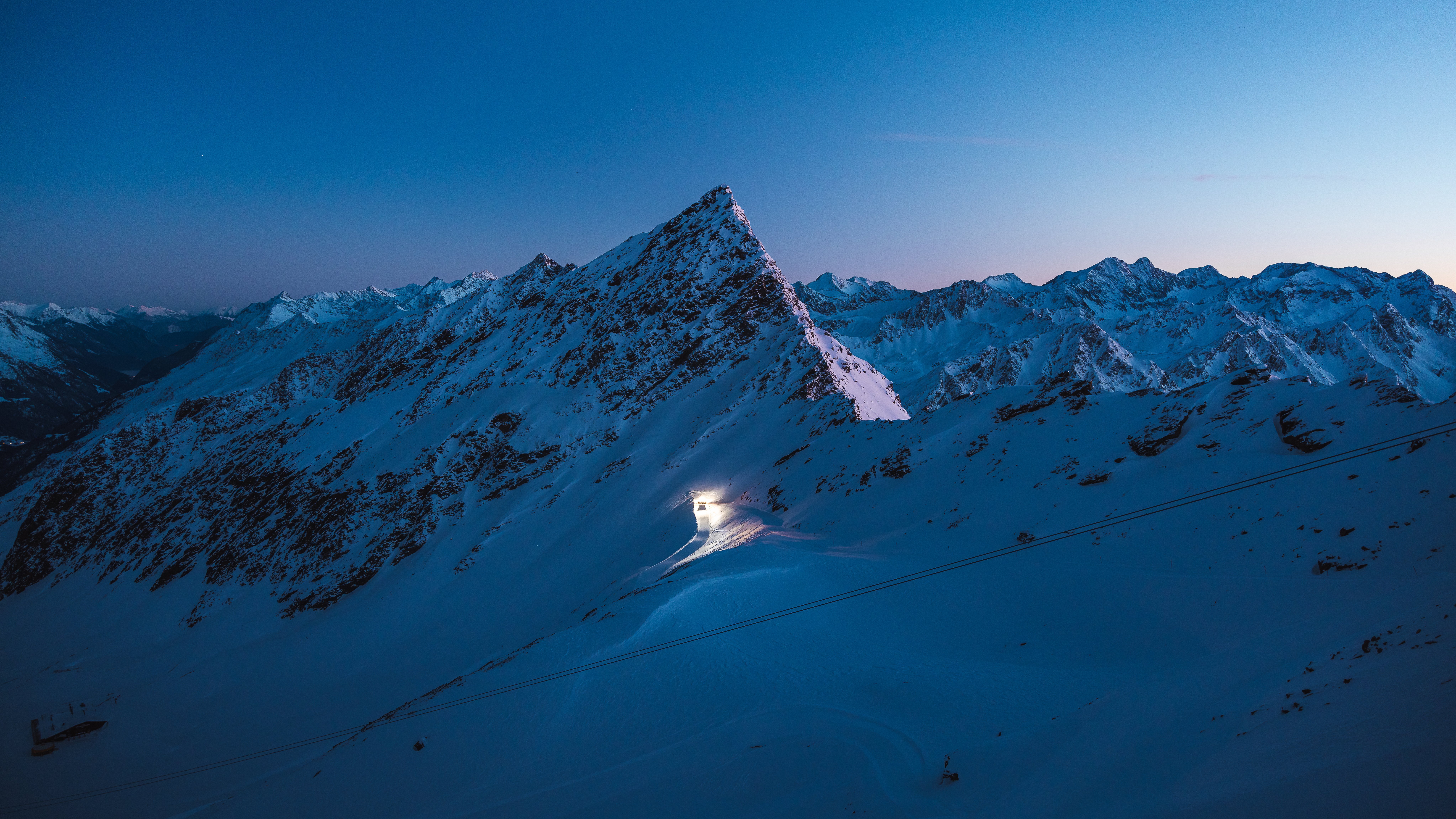 Majestic Twilight Over Snowy Peaks A snow-covered mountain peak glowing at sunset, surrounded by additional mountains in the background.