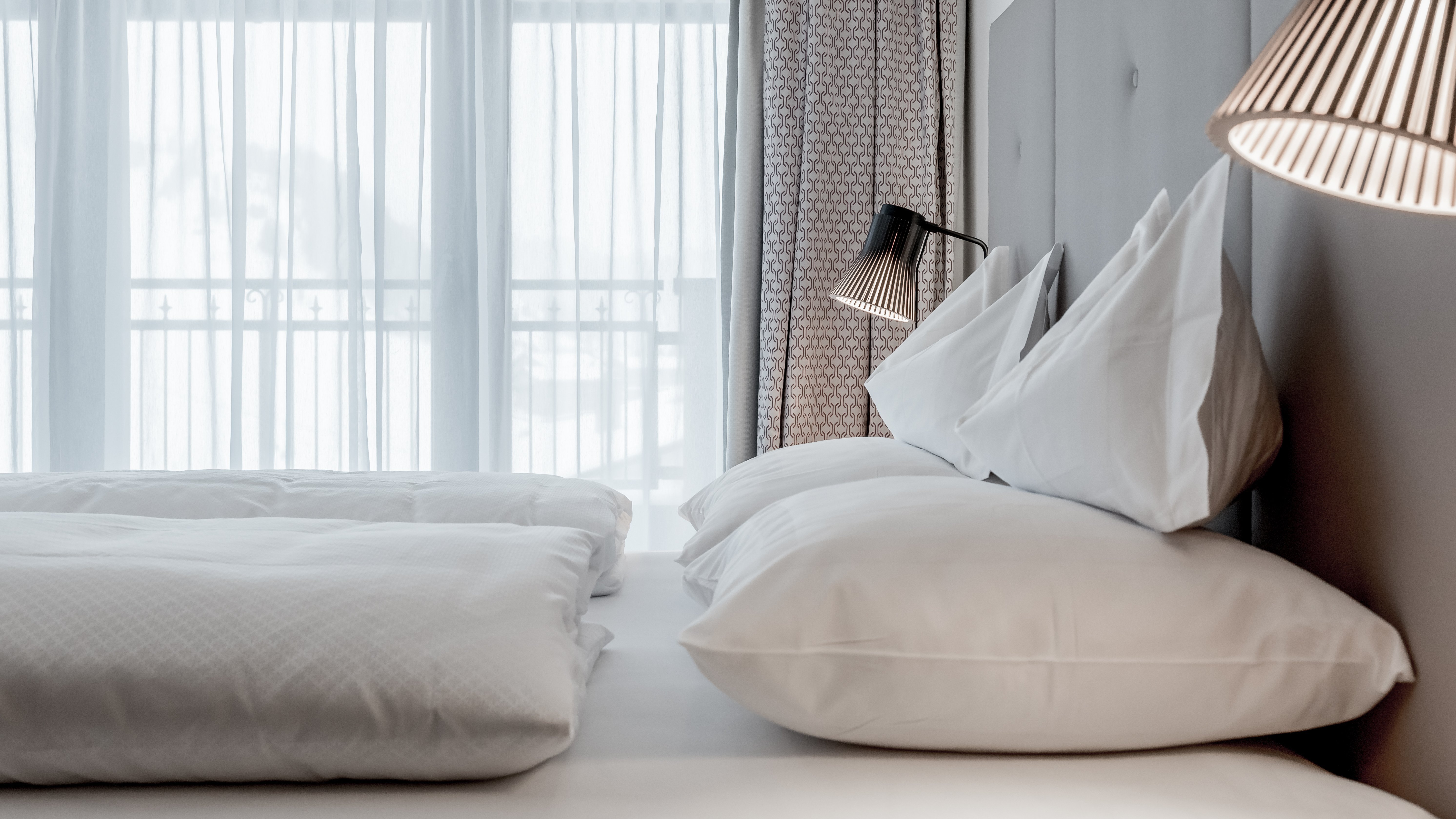 Moderne Hotelzimmer mit Lichtspiel Ein stilvolles Hotelzimmer mit einem großen Bett, weichen Kissen und lichtdurchfluteten Fenstern.