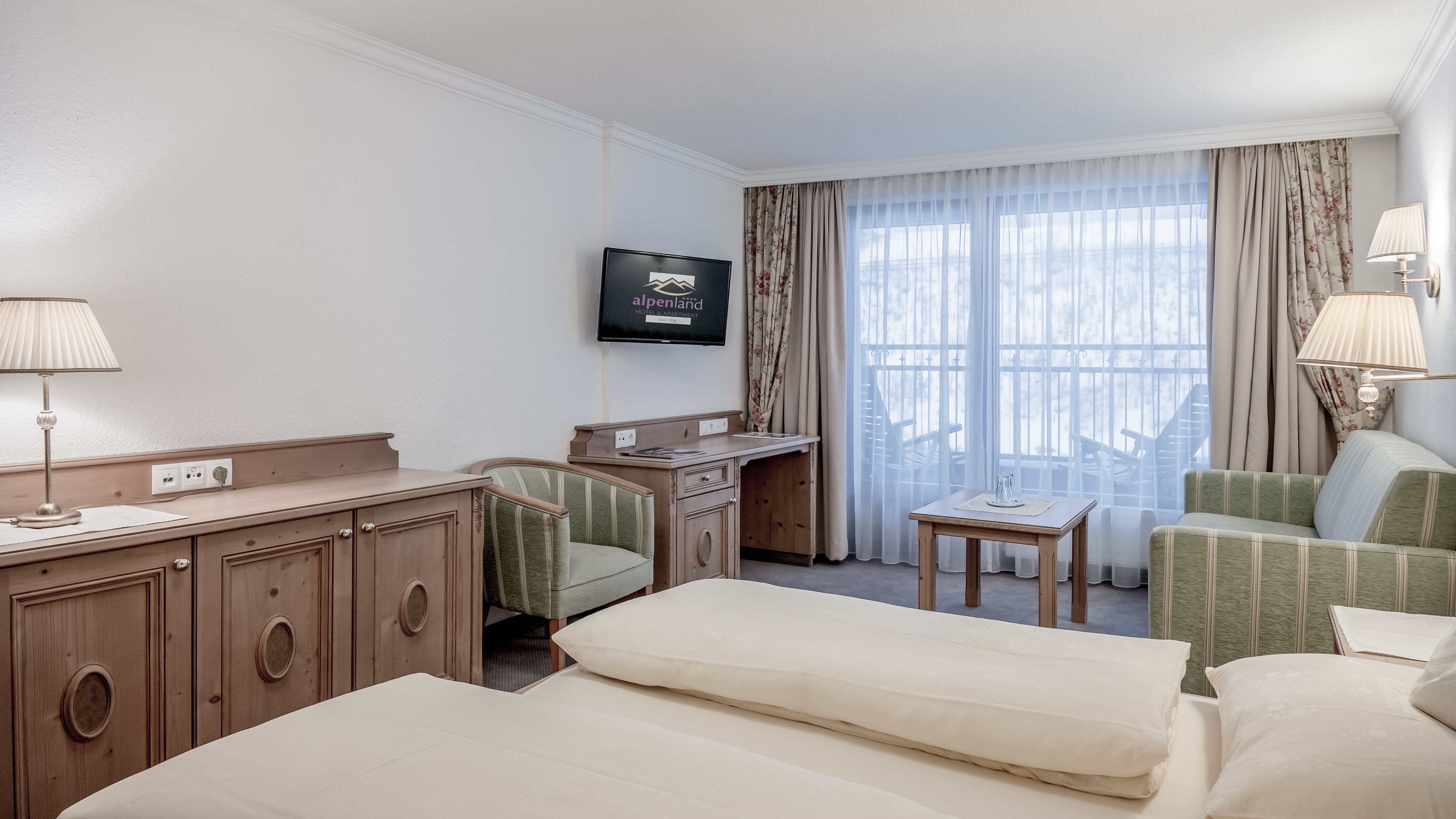 Moderne Hotelzimmer mit Wohlfühlcharakter Hotelzimmer mit Bett, Sitzbereich und Fernseher, große Fenster für Tageslicht. Schlichte Eleganz im Design.