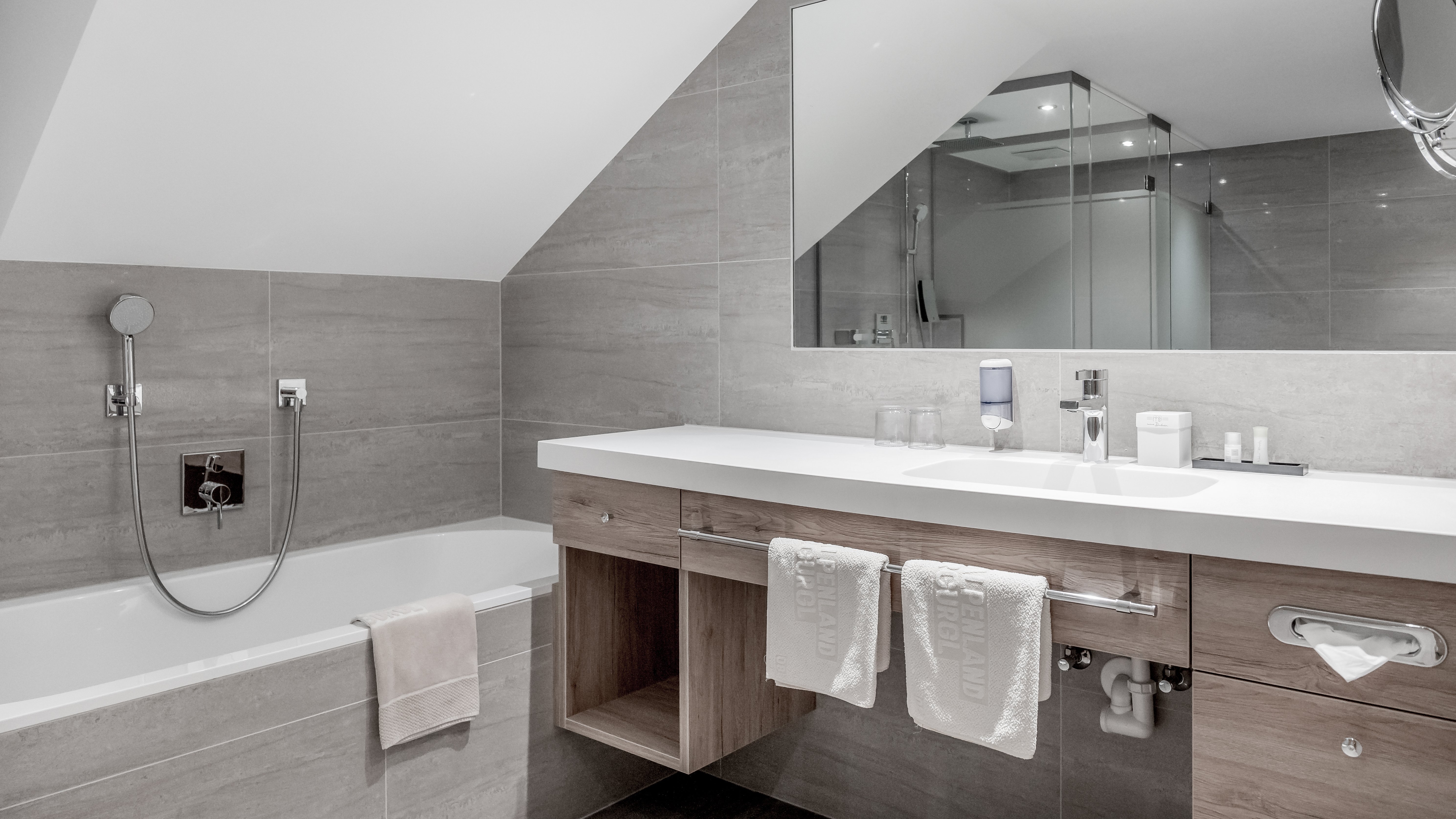 Moderne Badezimmergestaltung im Alpenland Modernes Badezimmer mit Badewanne, Waschbecken und Spiegel sowie zeitgenössischen Armaturen.