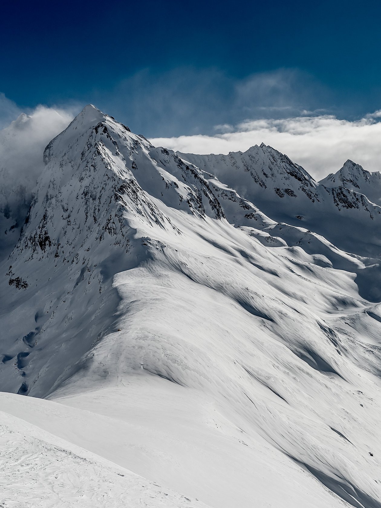 Schneebedeckte Berge im Winter Weite Schneelandschaft mit Berggipfeln unter blauem Himmel und Wolken, Winterlandschaft.