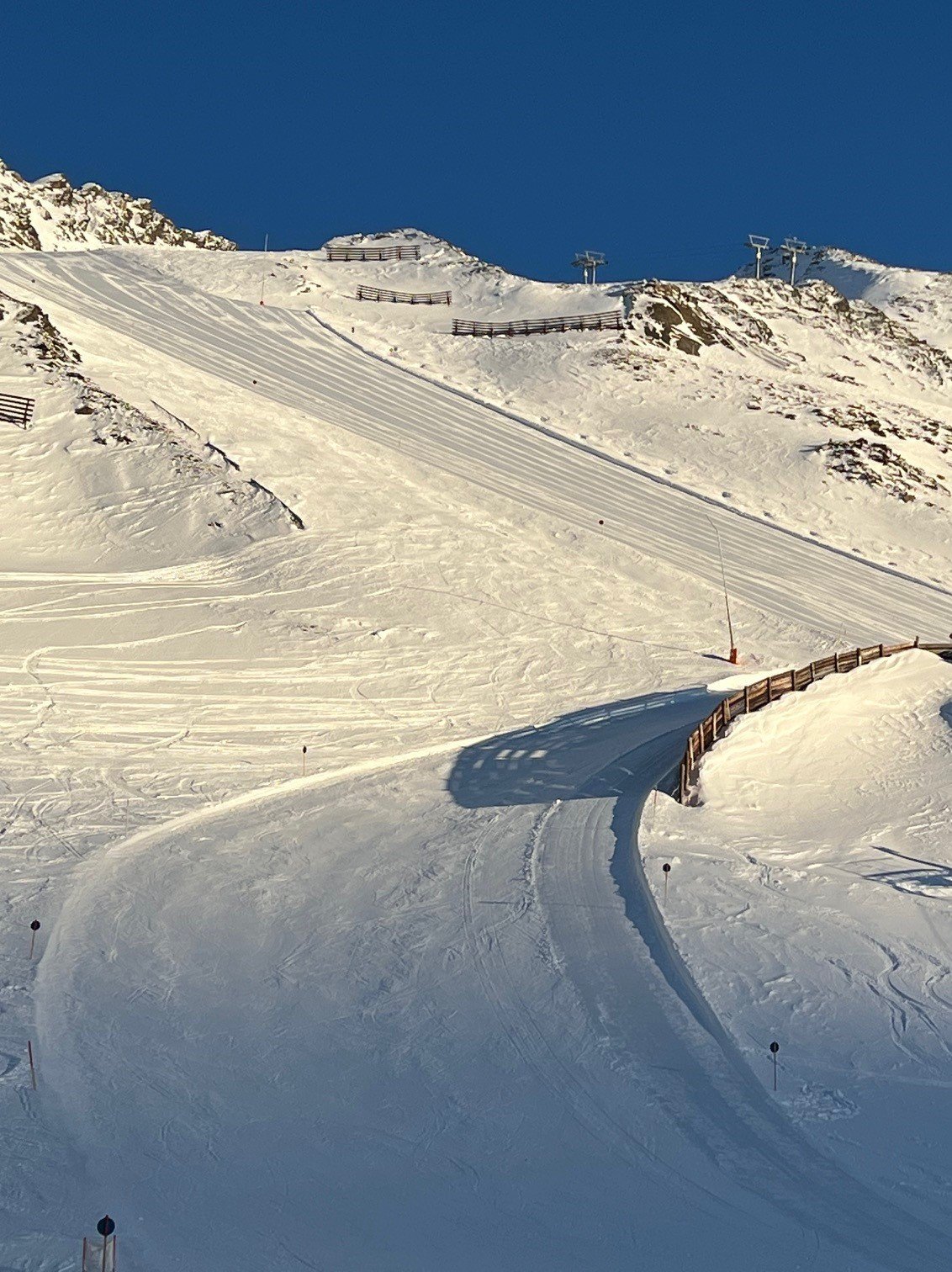 Skigebiet mit schneebedeckten Abfahrten und Bergpanorama unter blauem Himmel, geeignet für Wintersportler.