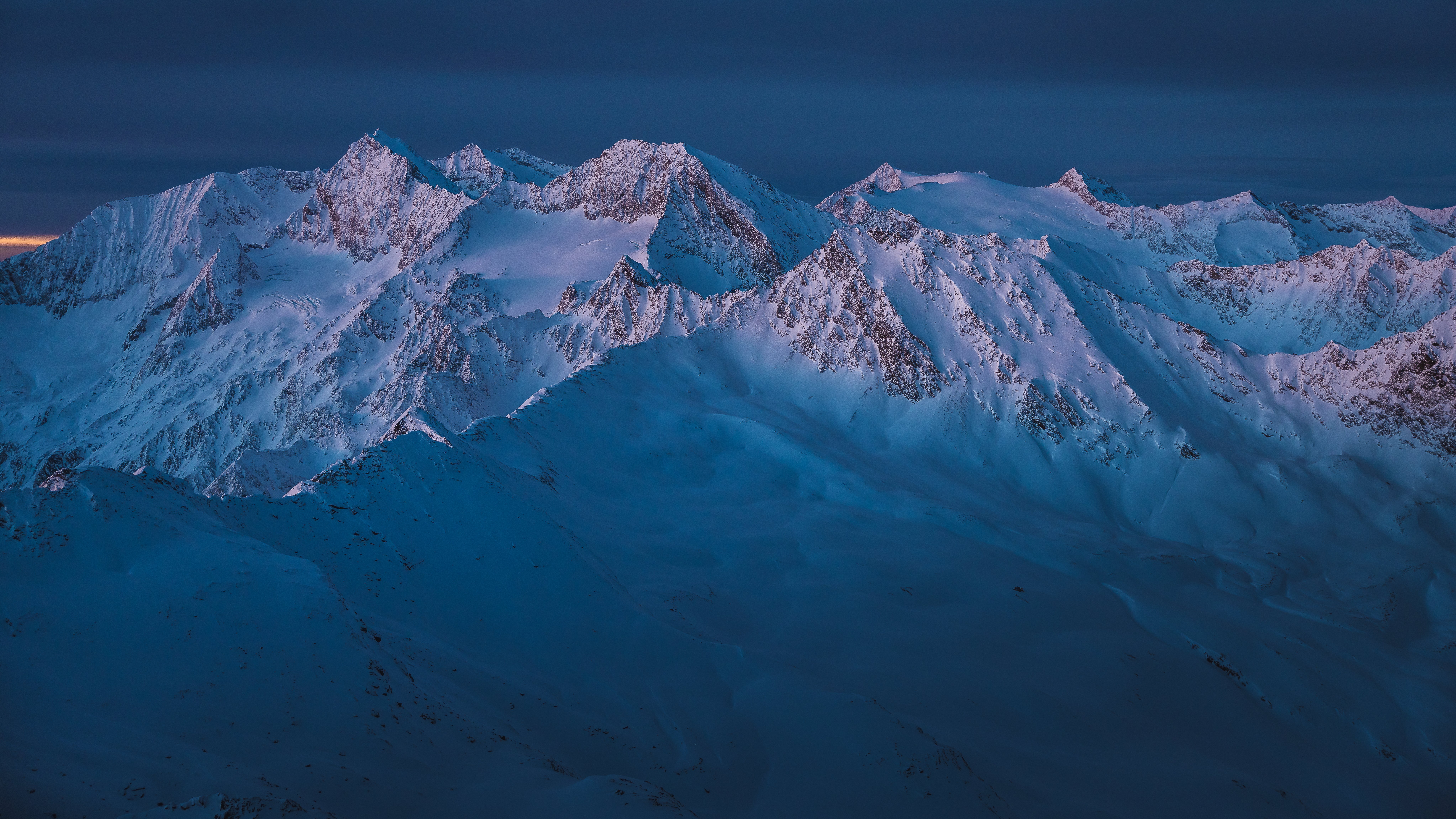 Majestic Snowy Peaks at Twilight A panoramic view of snow-covered mountains under a twilight sky showcasing rugged terrain and natural beauty