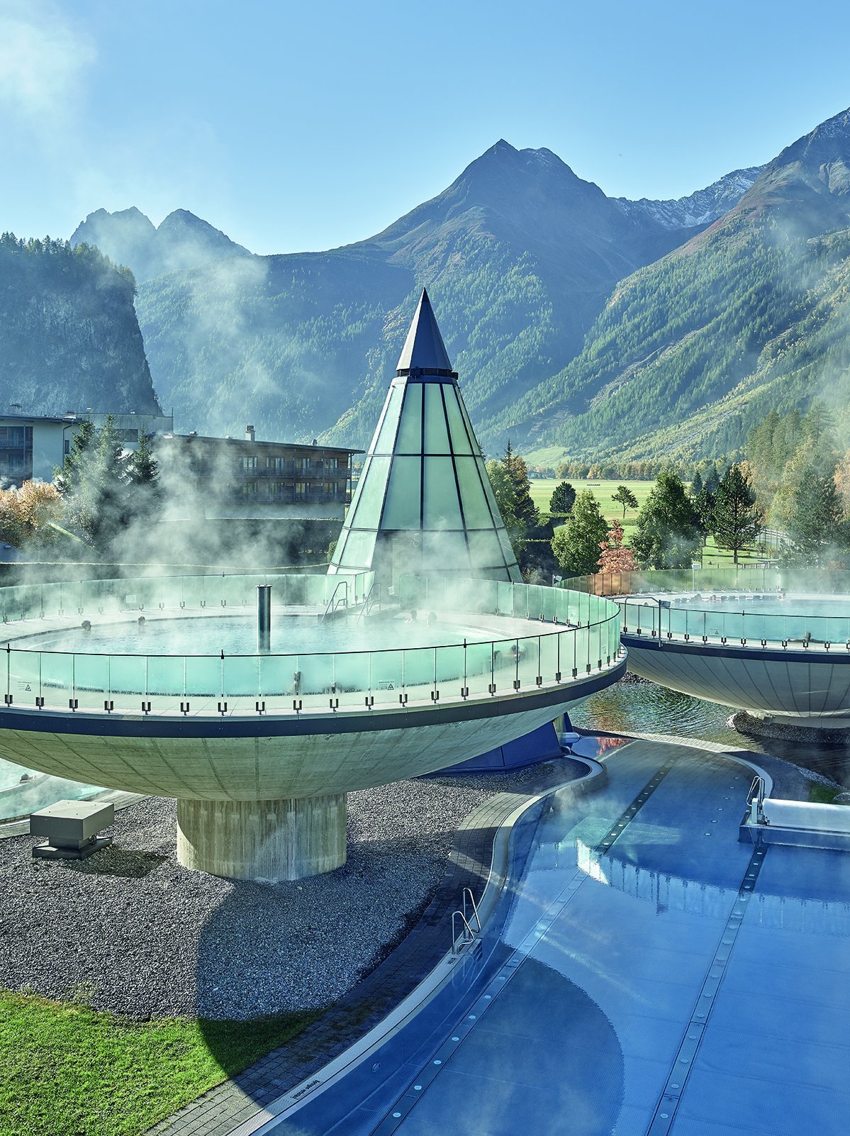 Spa facility with outdoor pools surrounded by mountains and greenery featuring unique architecture