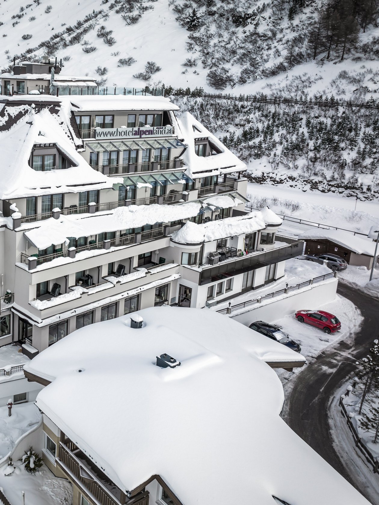Large mountain lodge blanketed in snow with surrounding mountains in winter scenery.