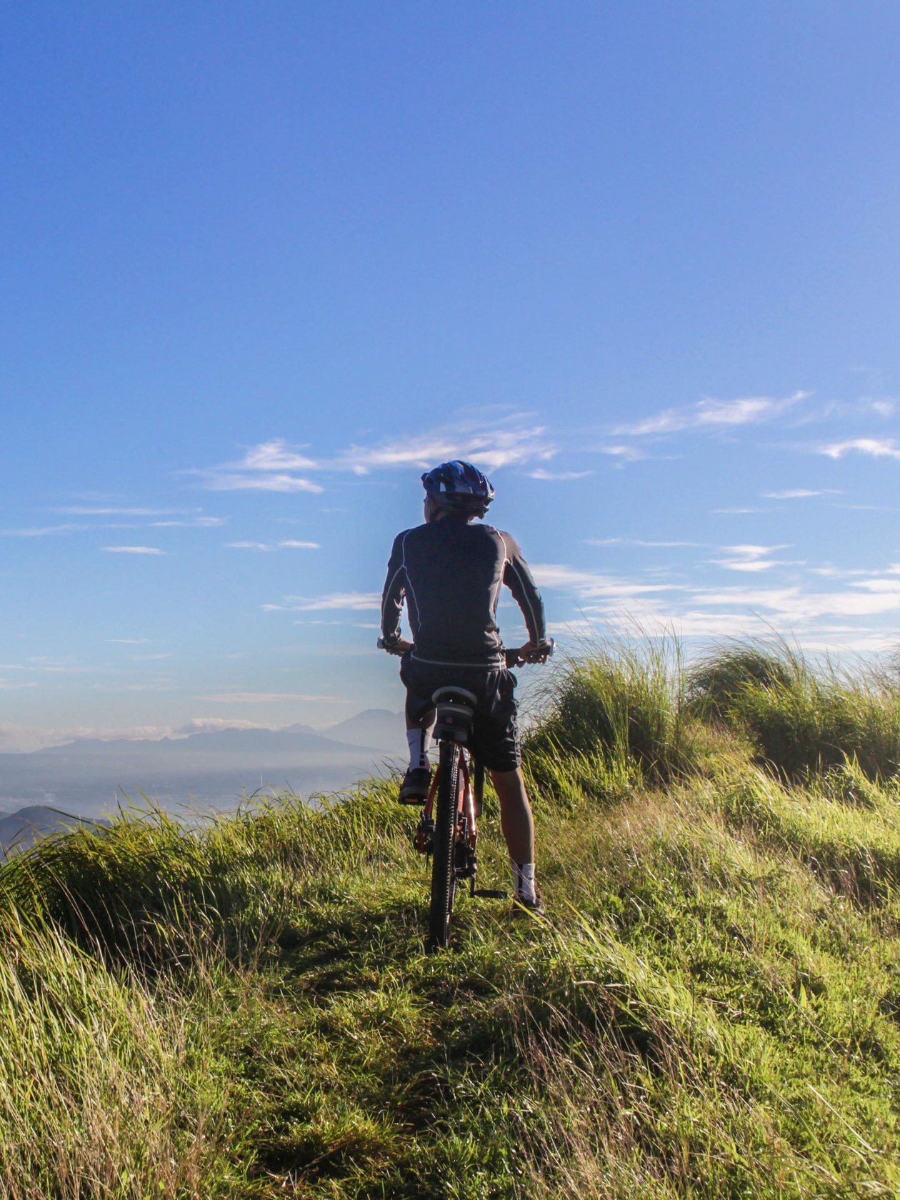 Person auf einem Mountainbike mit Blick auf eine weite Landschaft und Berge unter klarem Himmel
