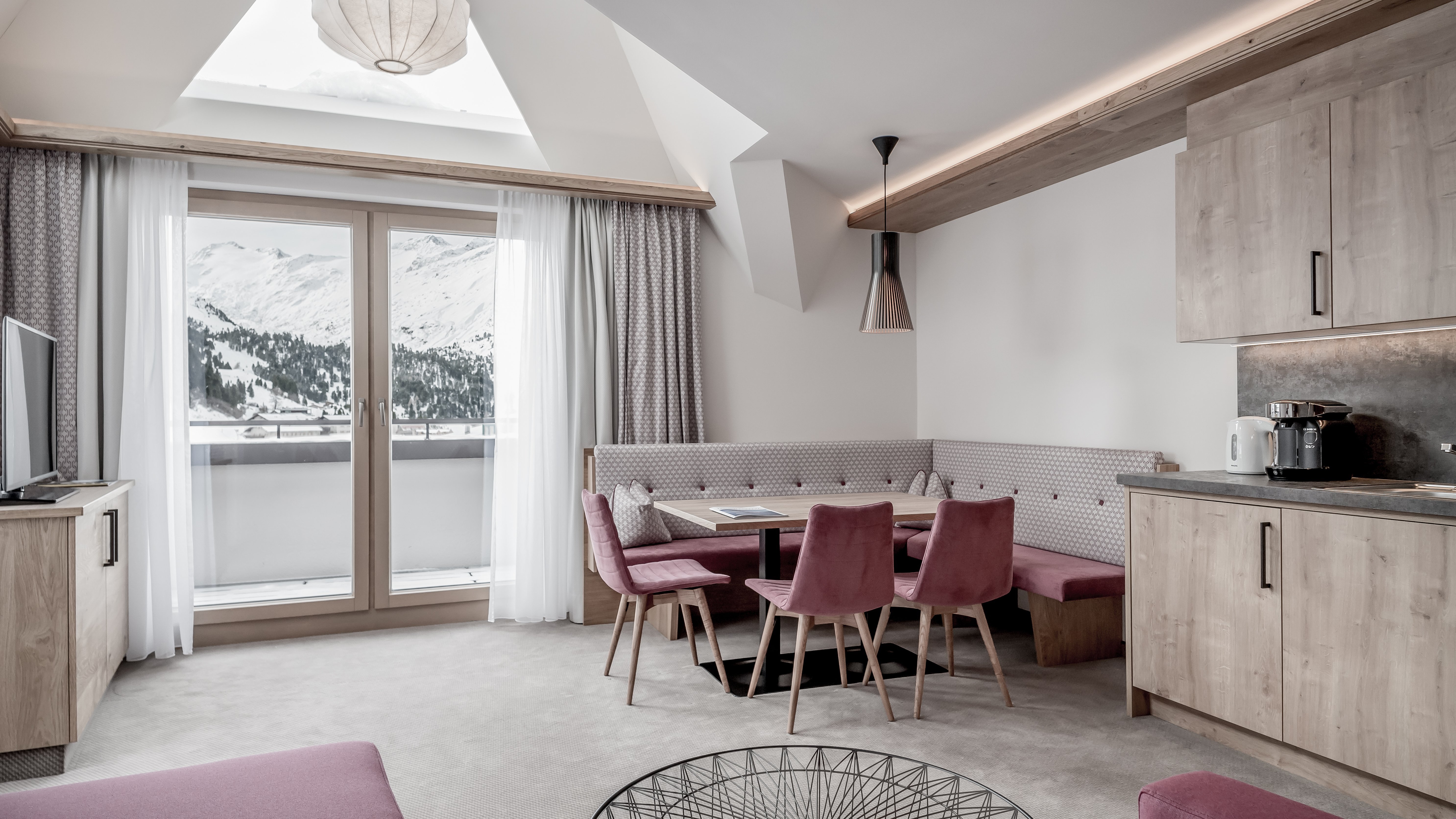 Moderne Hotel-Suite mit Bergblick Helle, moderne Suite mit gemütlichem Wohnbereich, Esstisch und großen Fenstern zur Bergsicht.