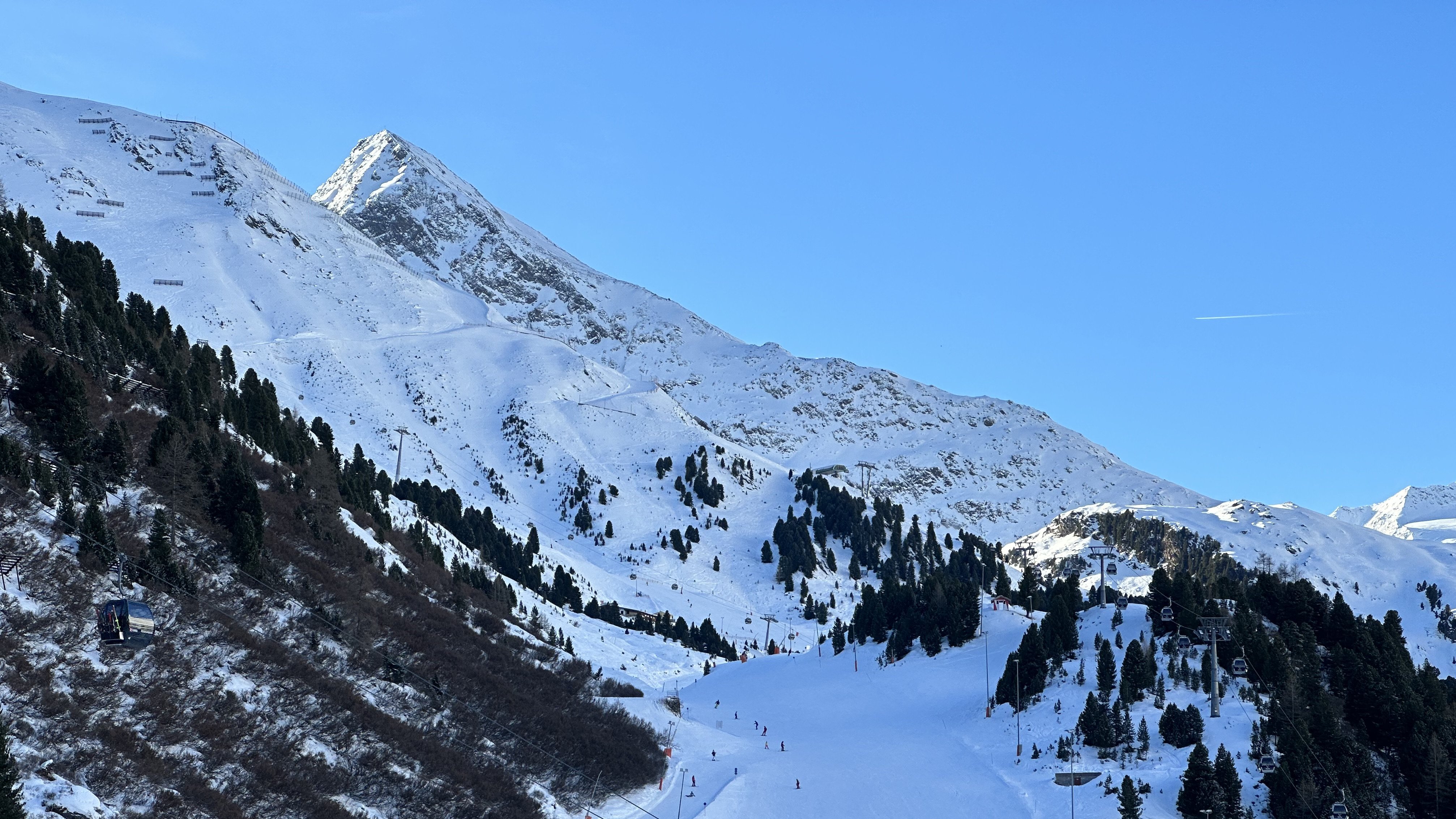 Winterfreuden auf den Pisten Schneebedeckte Berge mit Skilift und Skifahrern unter blauem Himmel in einem Skiressort.