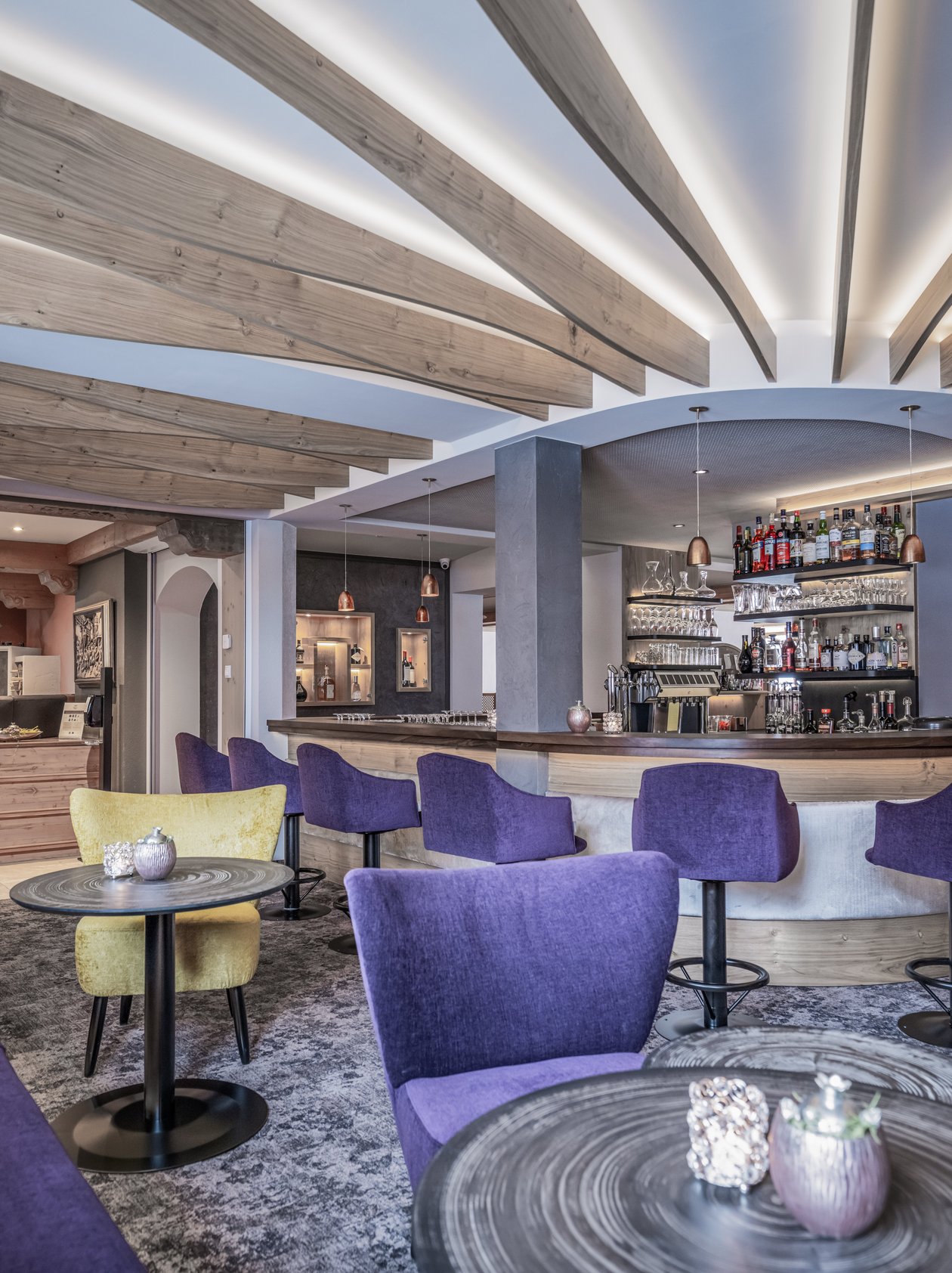 Moderne Hotelbar mit stilvollem Design Lounge Bar mit Holzdecken, modernen Sitzgelegenheiten in lila und gelb sowie einer gut gefüllten Bar.