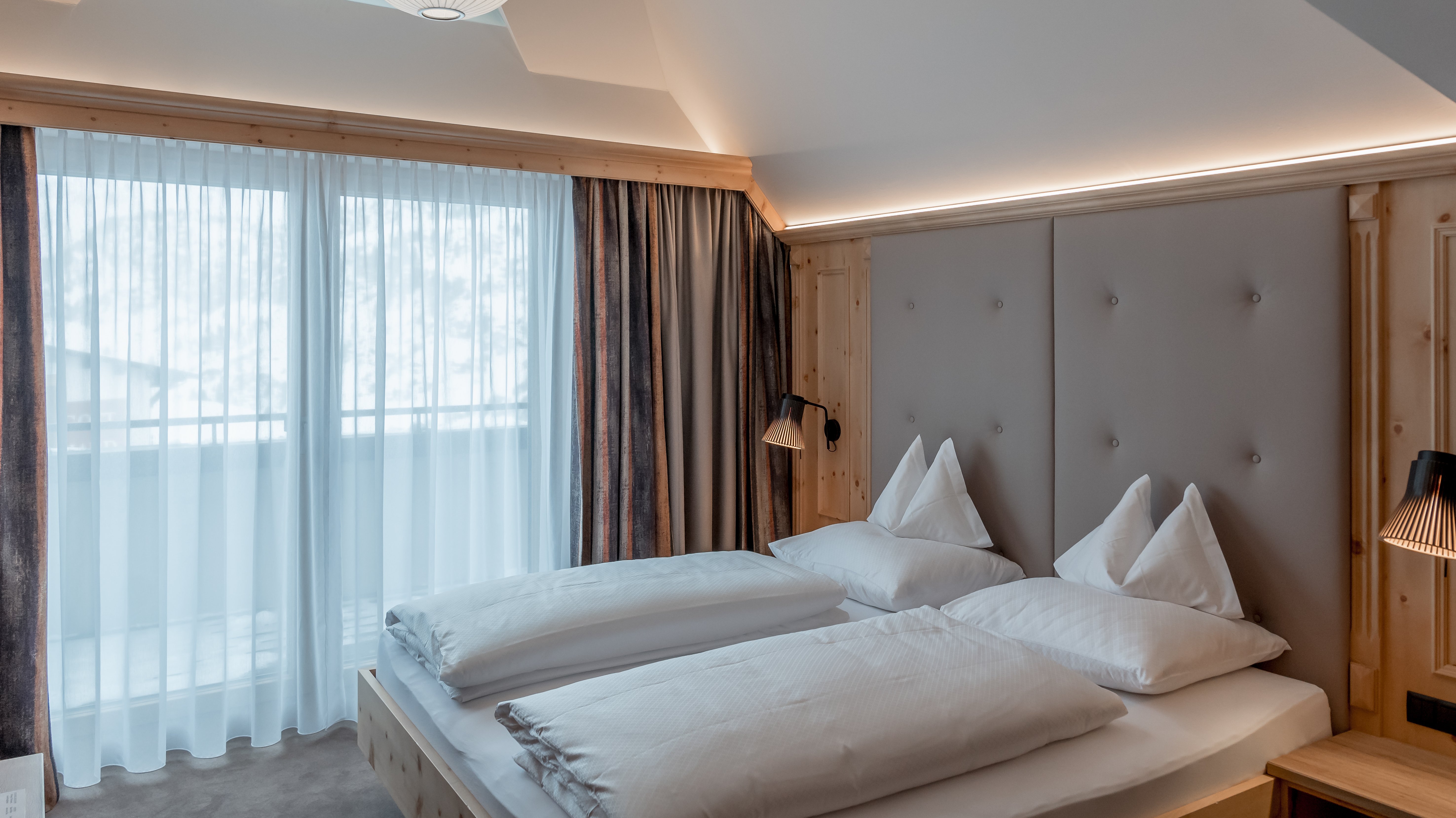 Moderne Schlafzimmergestaltung im Alpenland Helles Schlafzimmer mit Doppelbett und großen Fenstern, natürliche Lichtquelle durch Dachfenster.