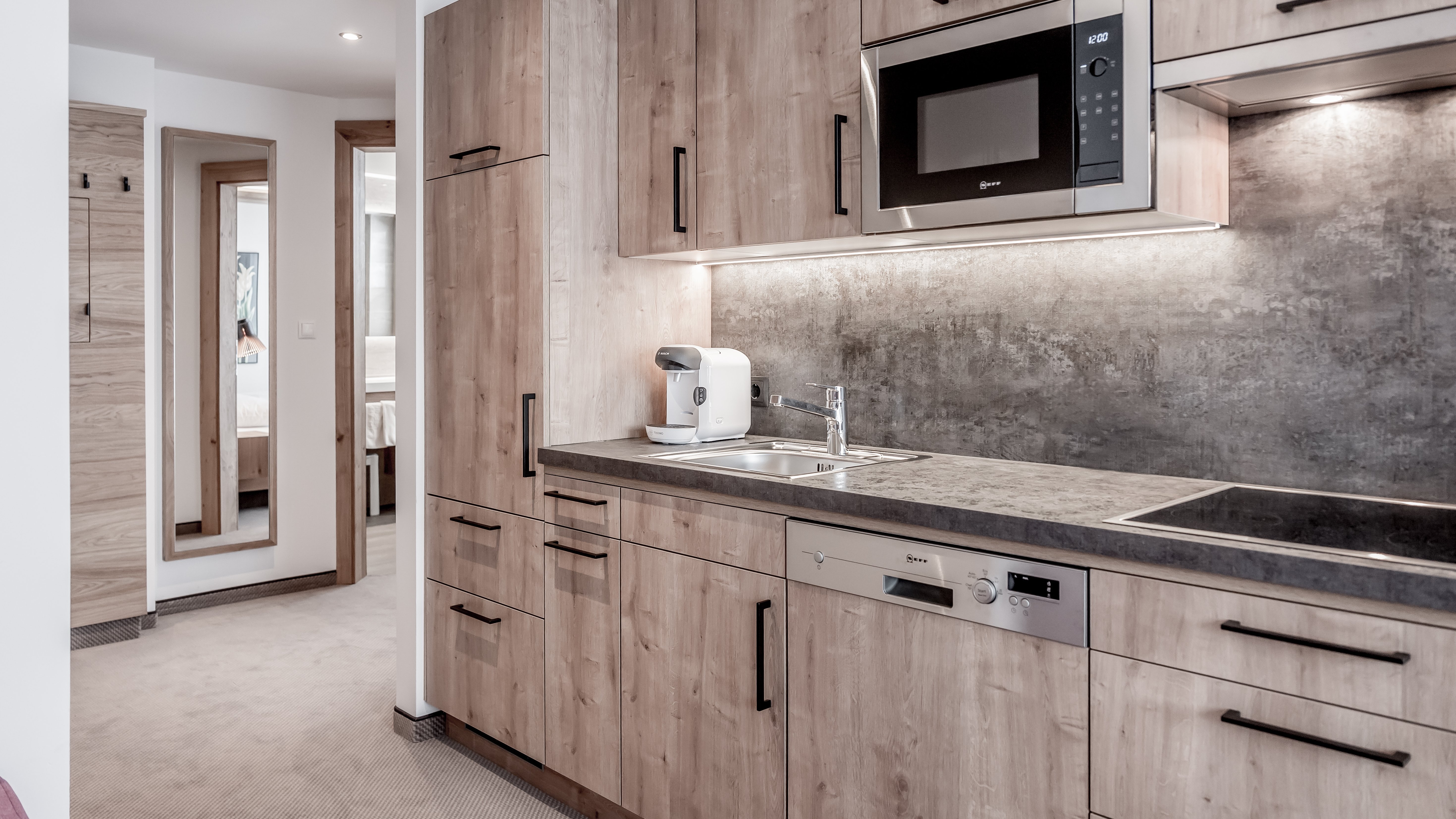 Moderne Küche für stilvolles Kochen Moderne Küche mit Holzschränken, eleganter Arbeitsplatte und Kochgeräten wie Mikrowelle und Kaffeemaschine.