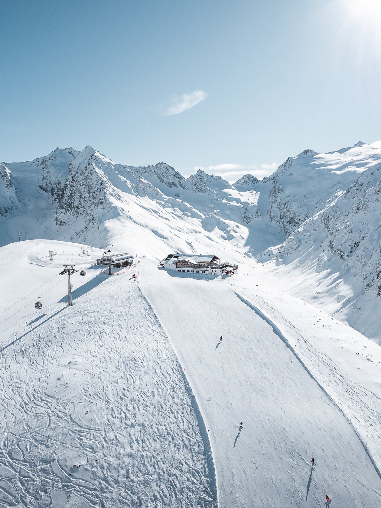 Luftaufnahme eines Skigebiets umgeben von schneebedeckten Bergen unter klarem Himmel