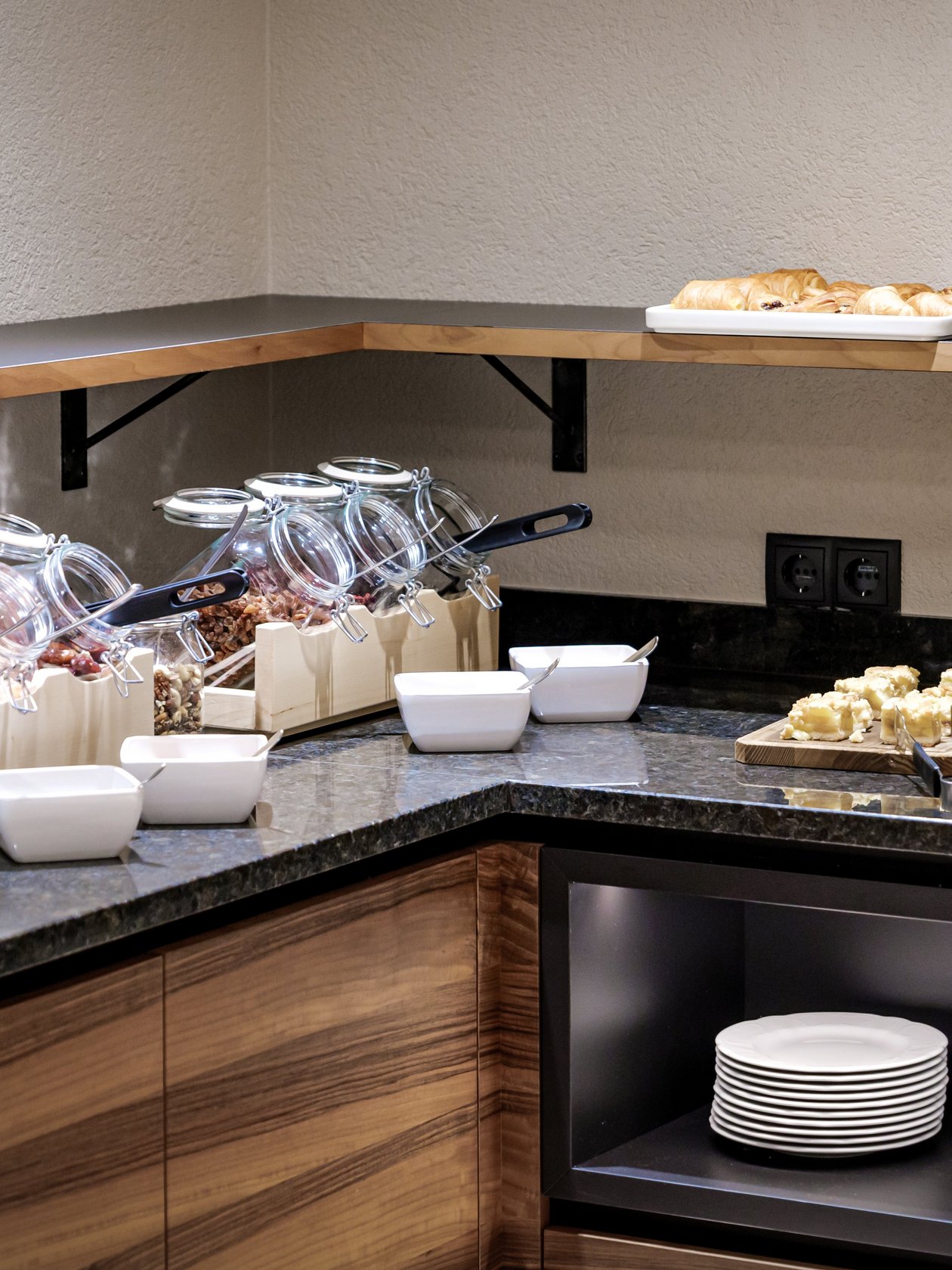 Anrichte mit verschiedenen Frühstücksbestandteilen wie Müsli und Gebäck in einem Hotel.