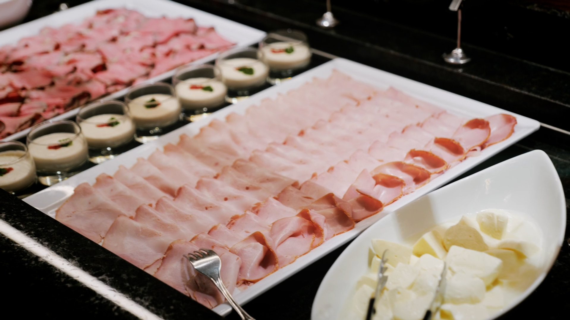 Vielfältige Fleischplatte zum Frühstück Buffet mit verschiedenen Arten von Aufschnitt und Vorspeisen auf Platten angerichtet.