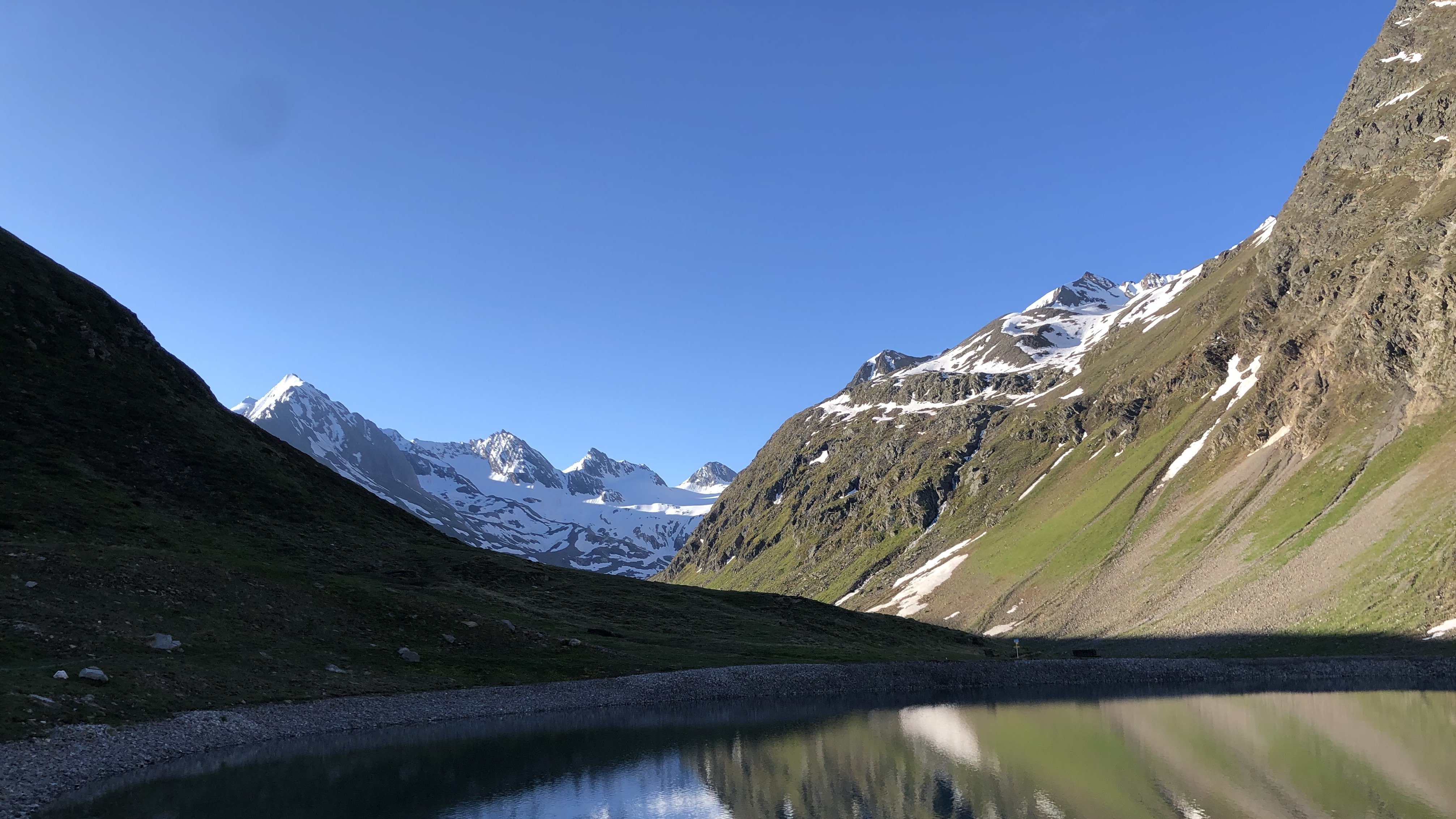 Bergsee mit klarer Wasseroberfläche, die Berge und den Himmel spiegelt. Natürliche Landschaft.