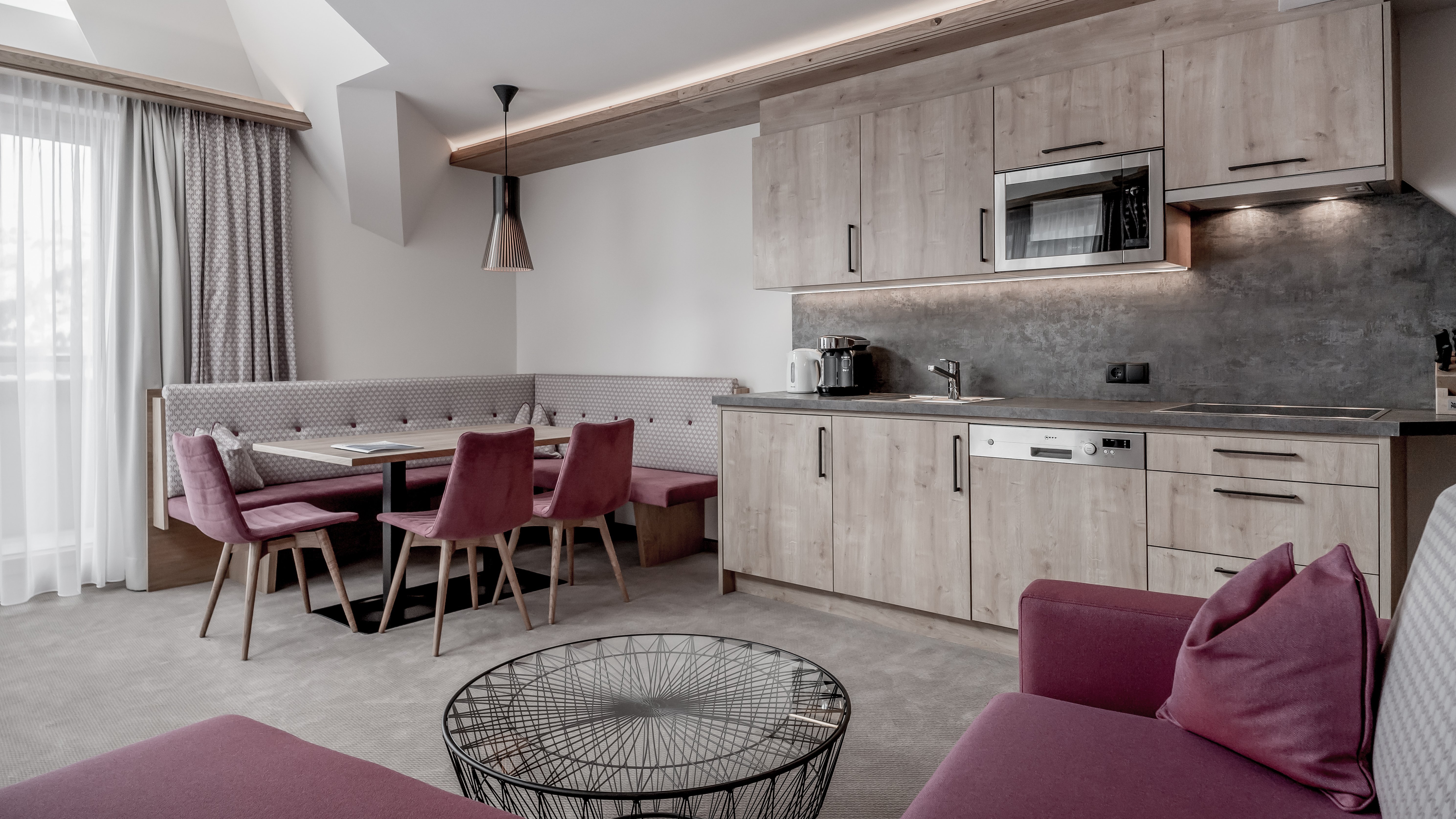 Moderne Küche im Alpenland Offene Küchenlandschaft mit Holzschränken und einem Esstisch in zeitgenössischem Design.