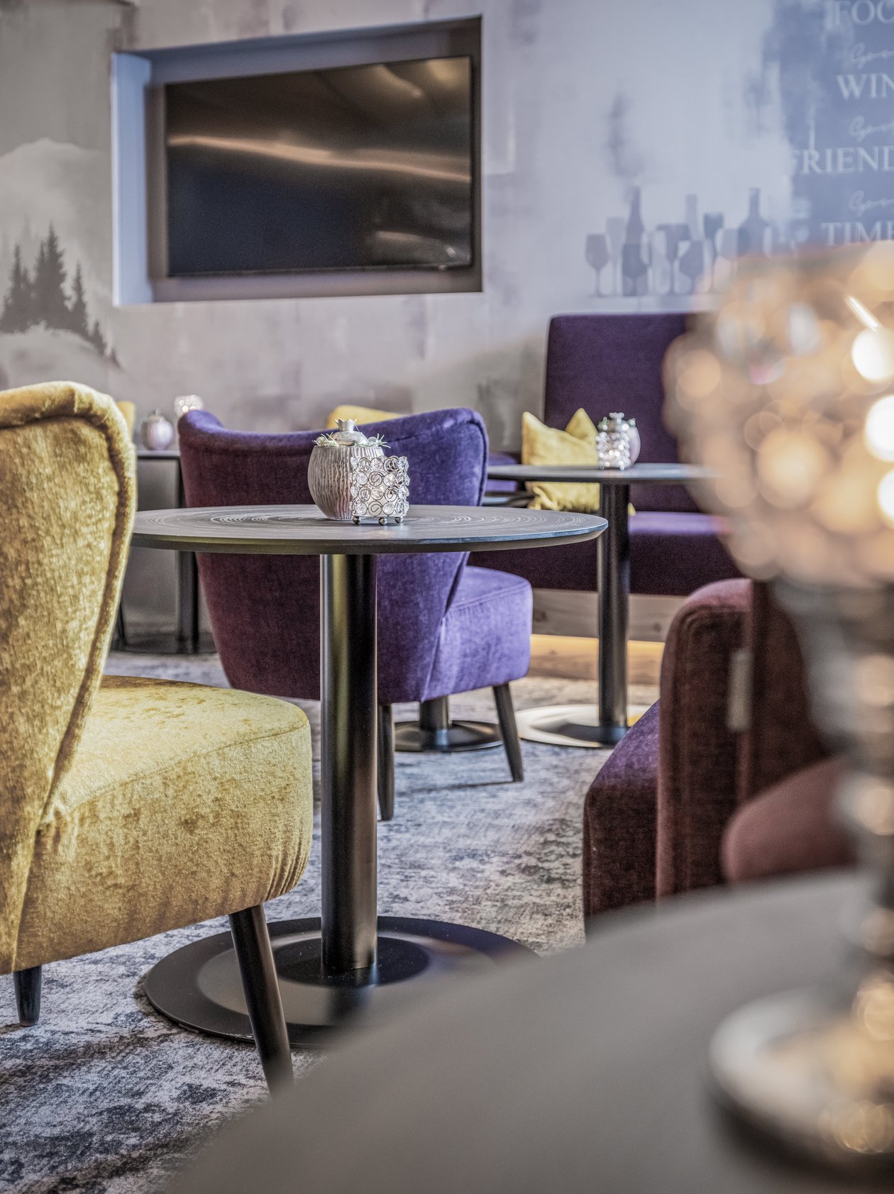 A cozy lounge with colorful chairs, tables, and a decorative candle holder in the foreground.