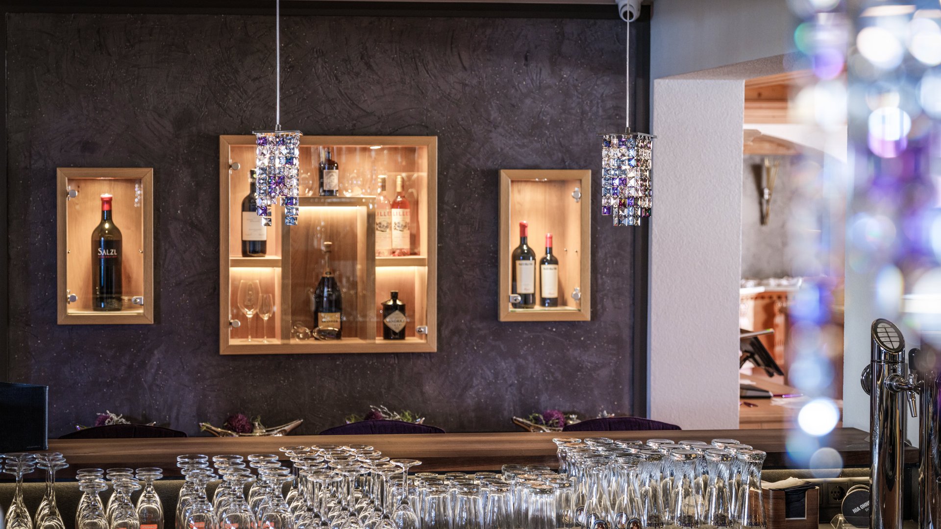 Barbereich mit Weinsortiment und Gläsern auf der Theke in einem Restaurantinterieur.