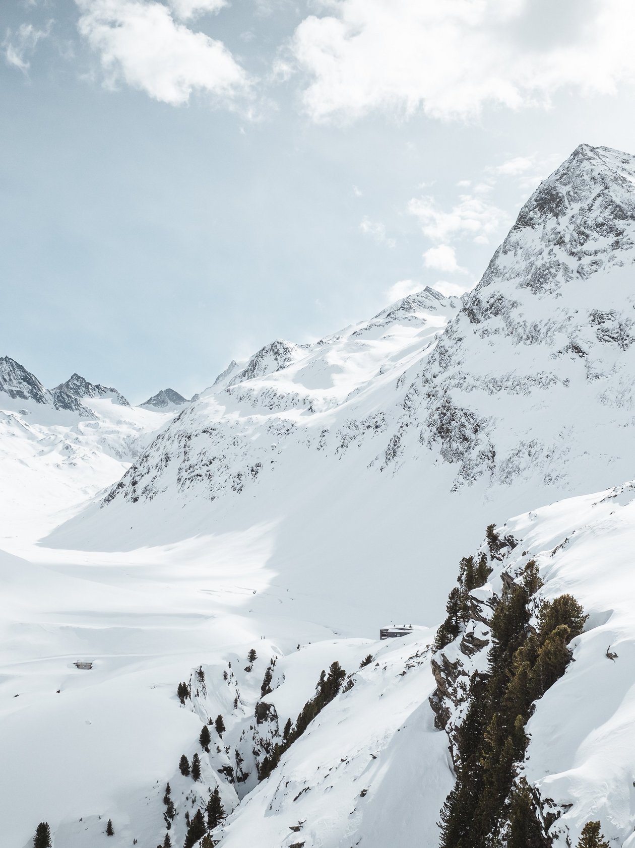 Weite winterliche Landschaft mit schneebedeckten Bergen und klarem Himmel in den Alpen.