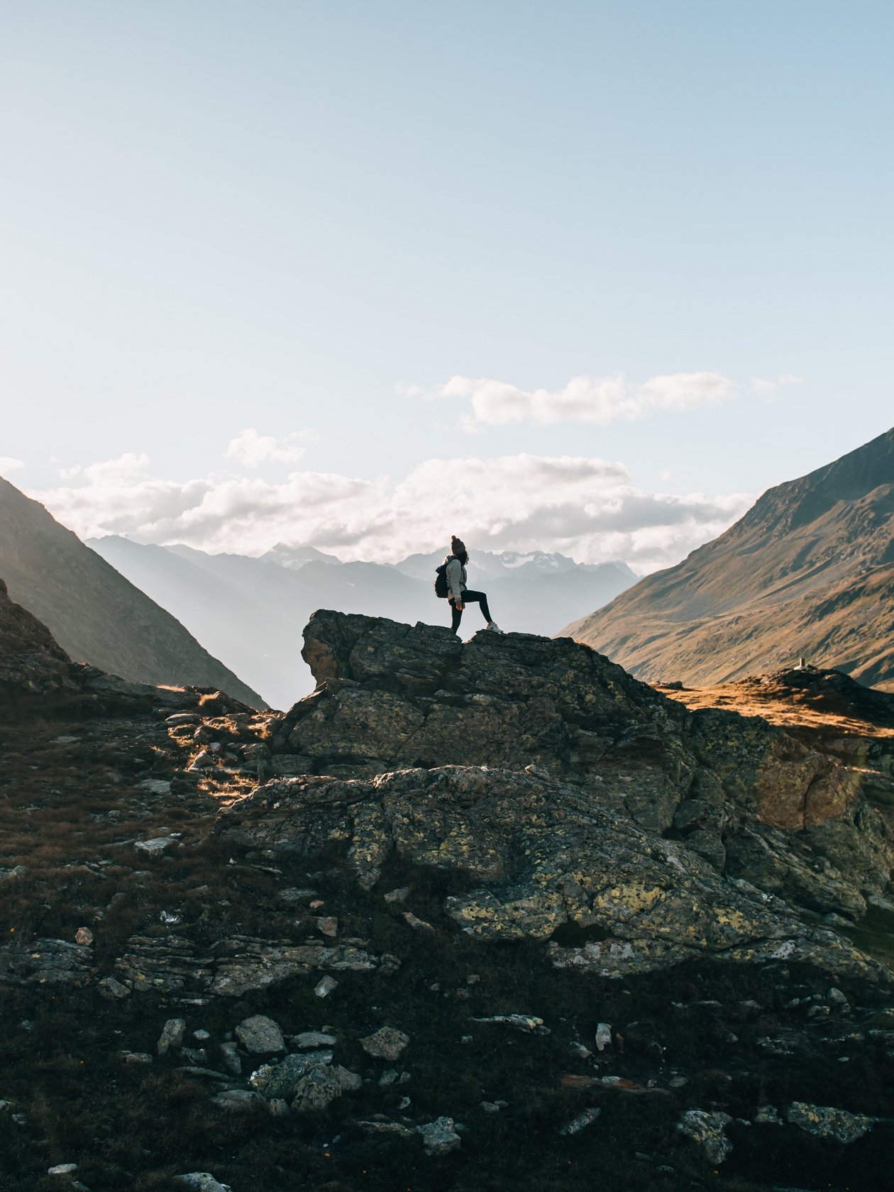 Berglandschaft mit Sonnenaufgang Person steht auf einem großen Felsen in einer Berglandschaft während des Sonnenaufgangs