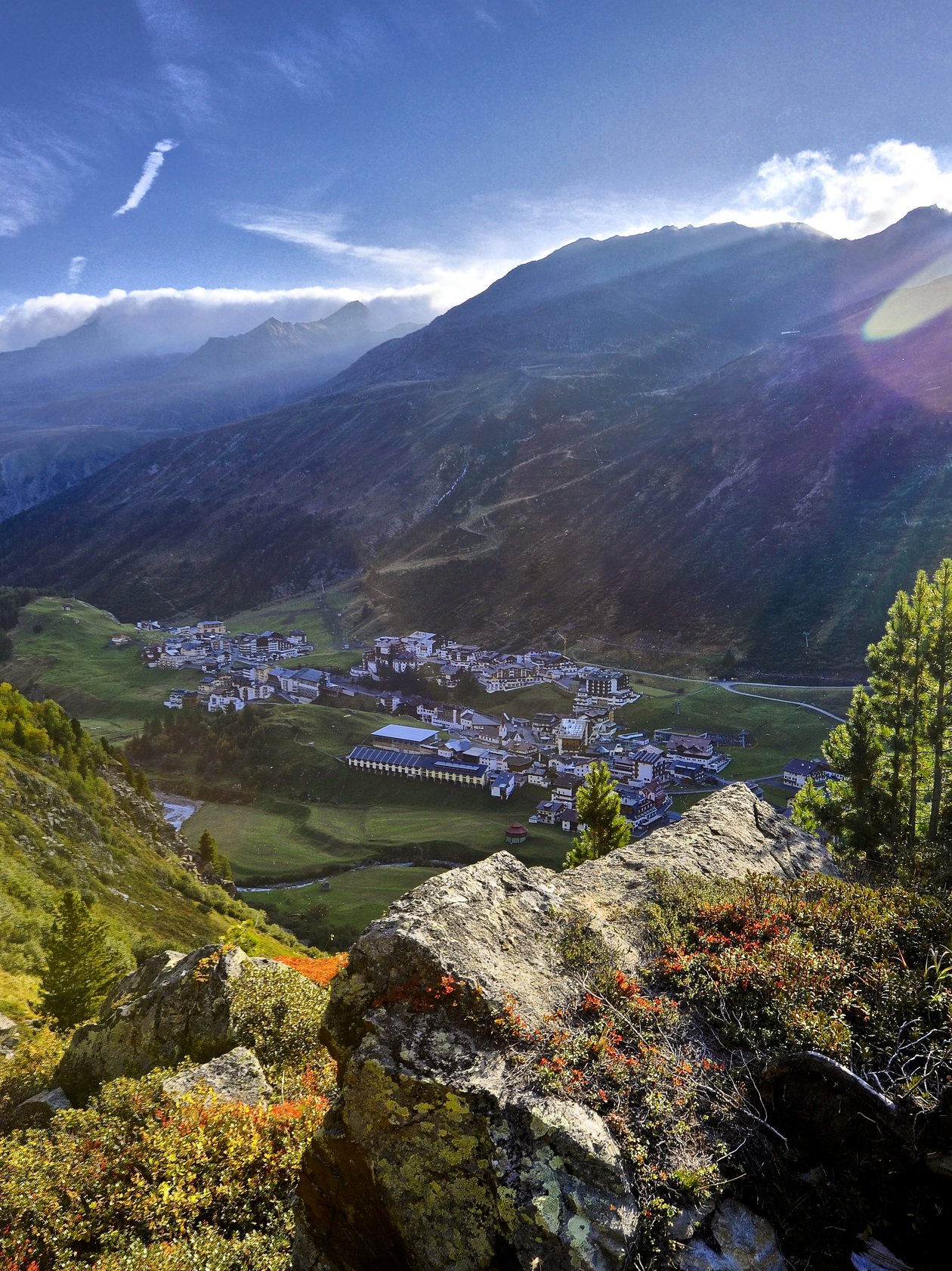 Panoramablick auf eine Berglandschaft mit Tal und Dorf bei Sonnenaufgang in der Natur.