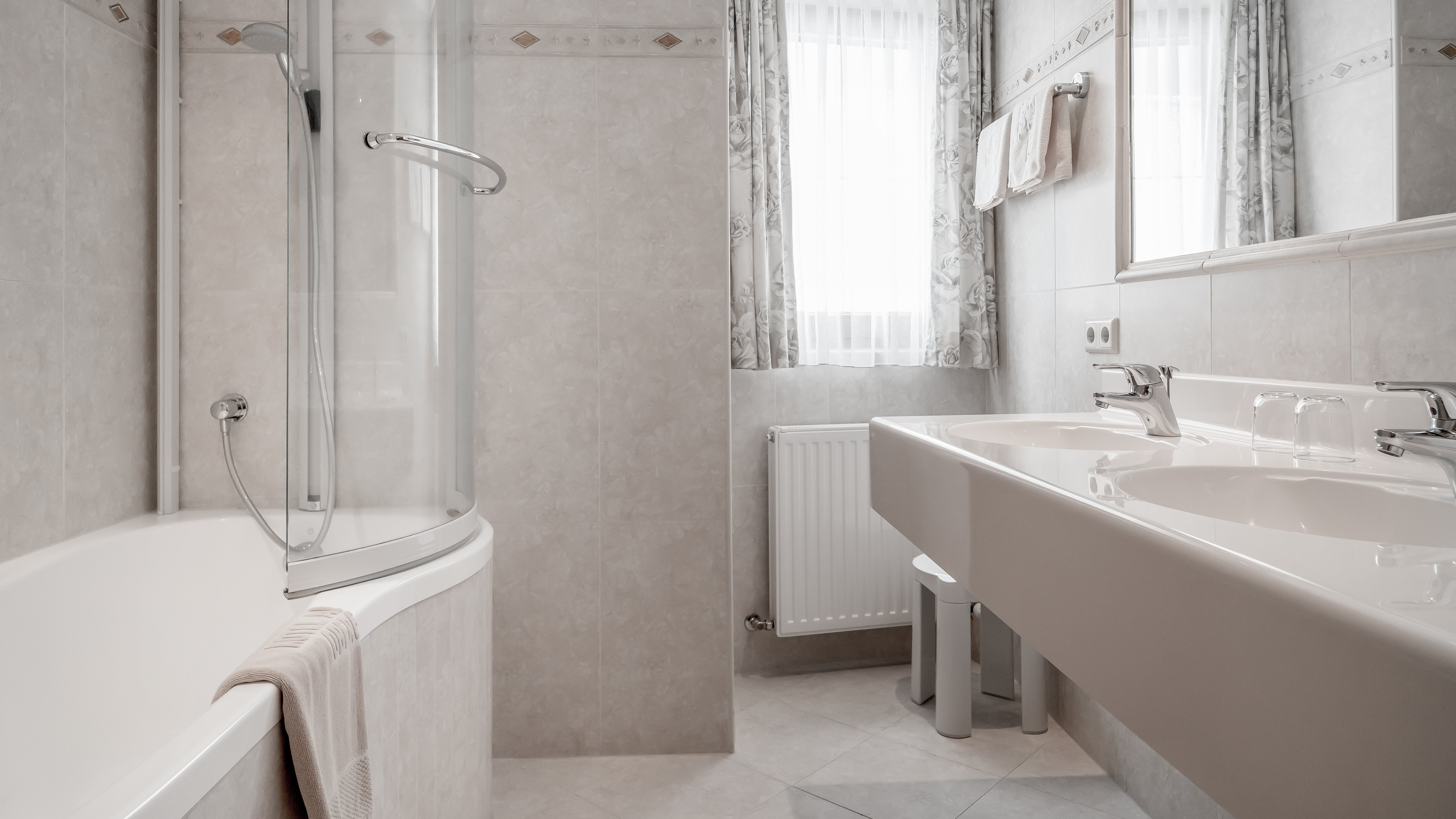 Modernes Badezimmer im Alpenland Zeitgemäß gestaltetes Badezimmer mit Dusche, Badewanne und Doppelwaschbecken unter großen Fenstern.