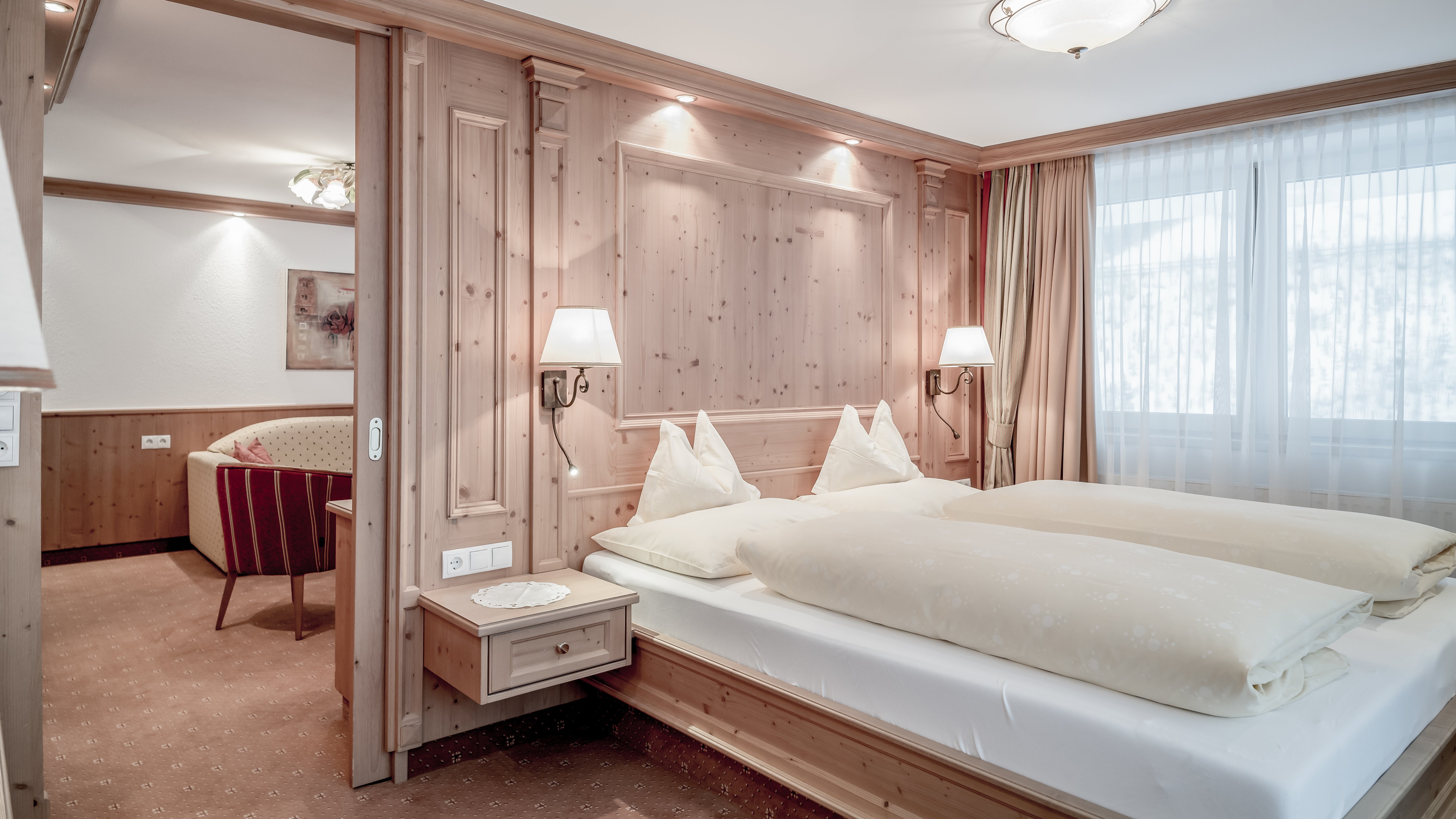 Gemütliches Zimmer im Alpenland Hotelzimmer mit Holzverkleidung, Doppelbett und Sitzbereich im Hintergrund von Alpenland.