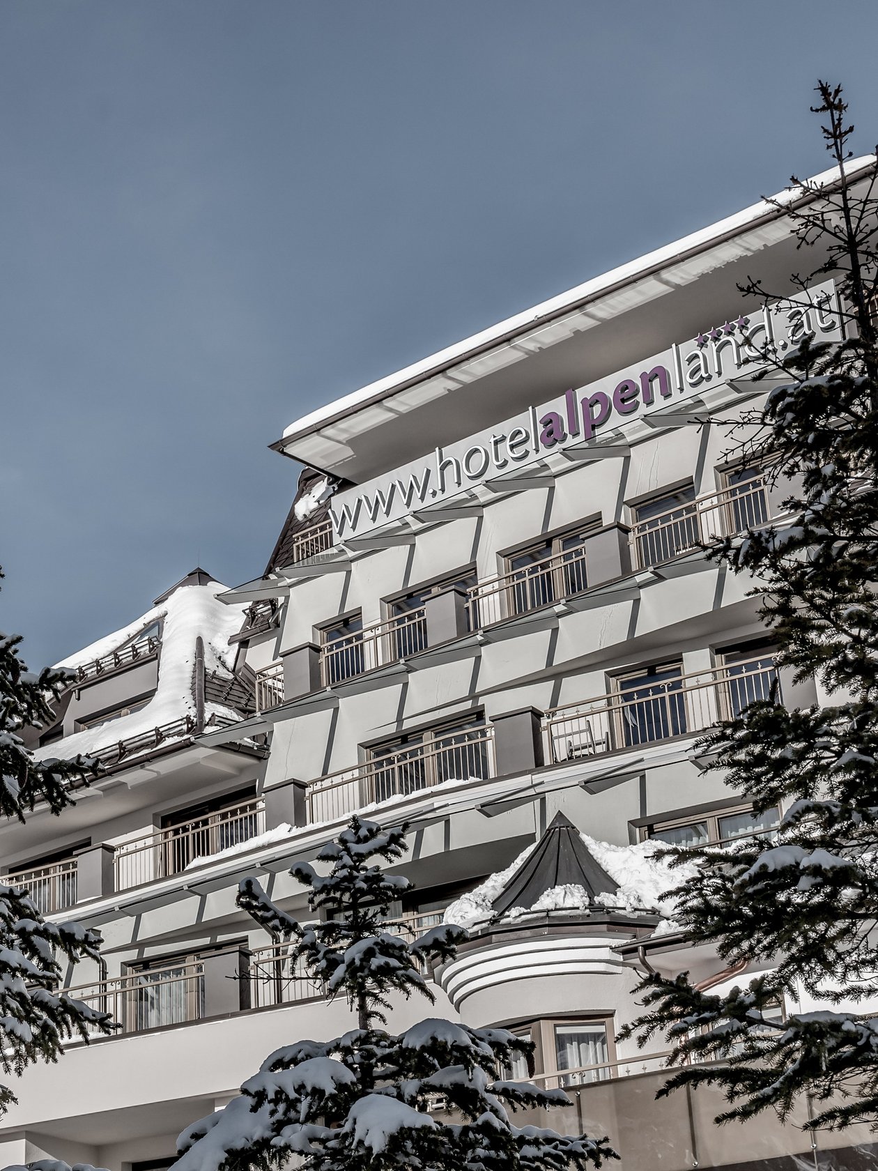 Hotelgebäude in Schneedecke unter klarem Himmel mit Bergen im Hintergrund für Winteraufenthalt.