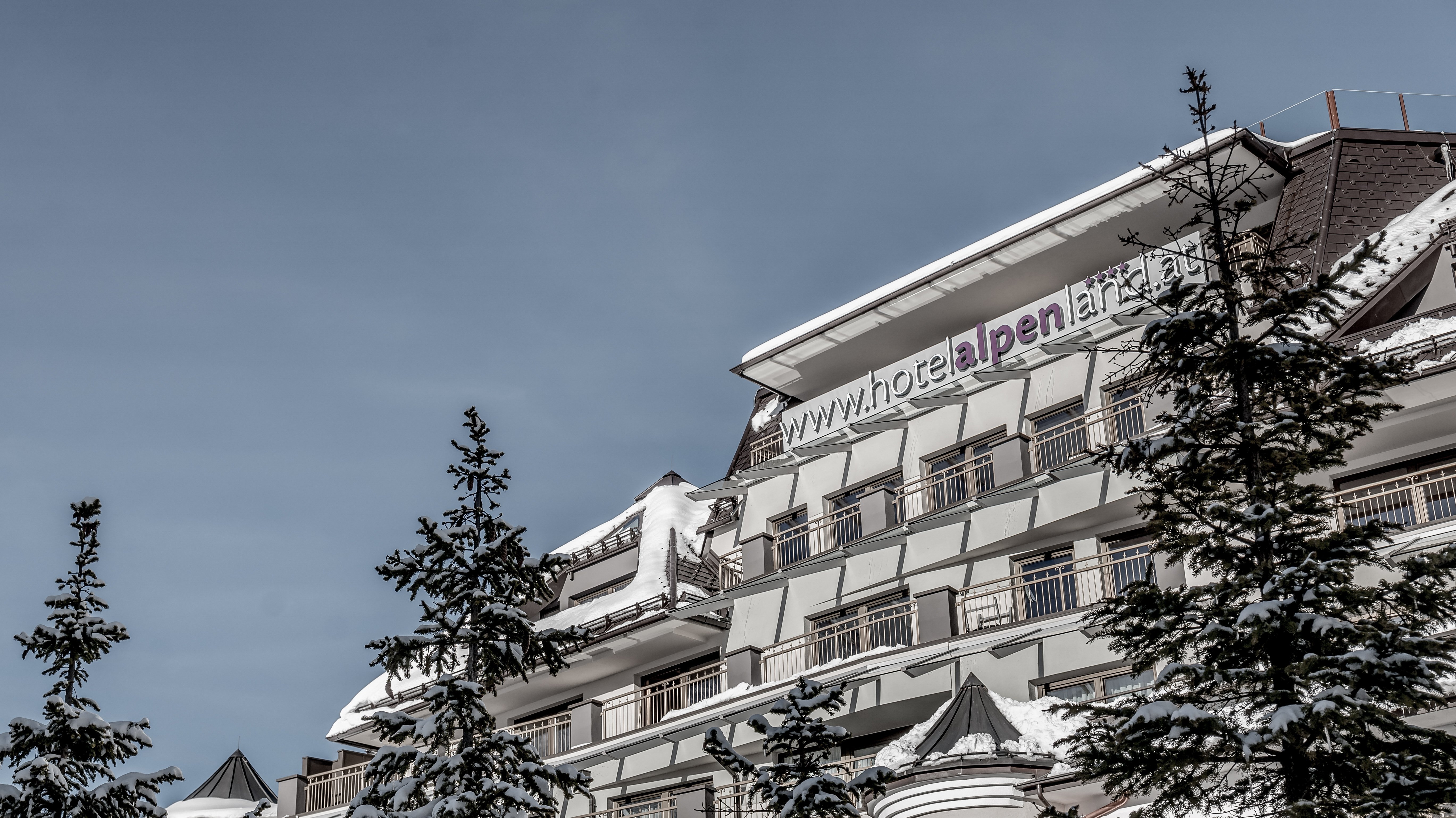 Wintertraum im Alpenland Hotelgebäude in Schneedecke unter klarem Himmel mit Bergen im Hintergrund für Winteraufenthalt.