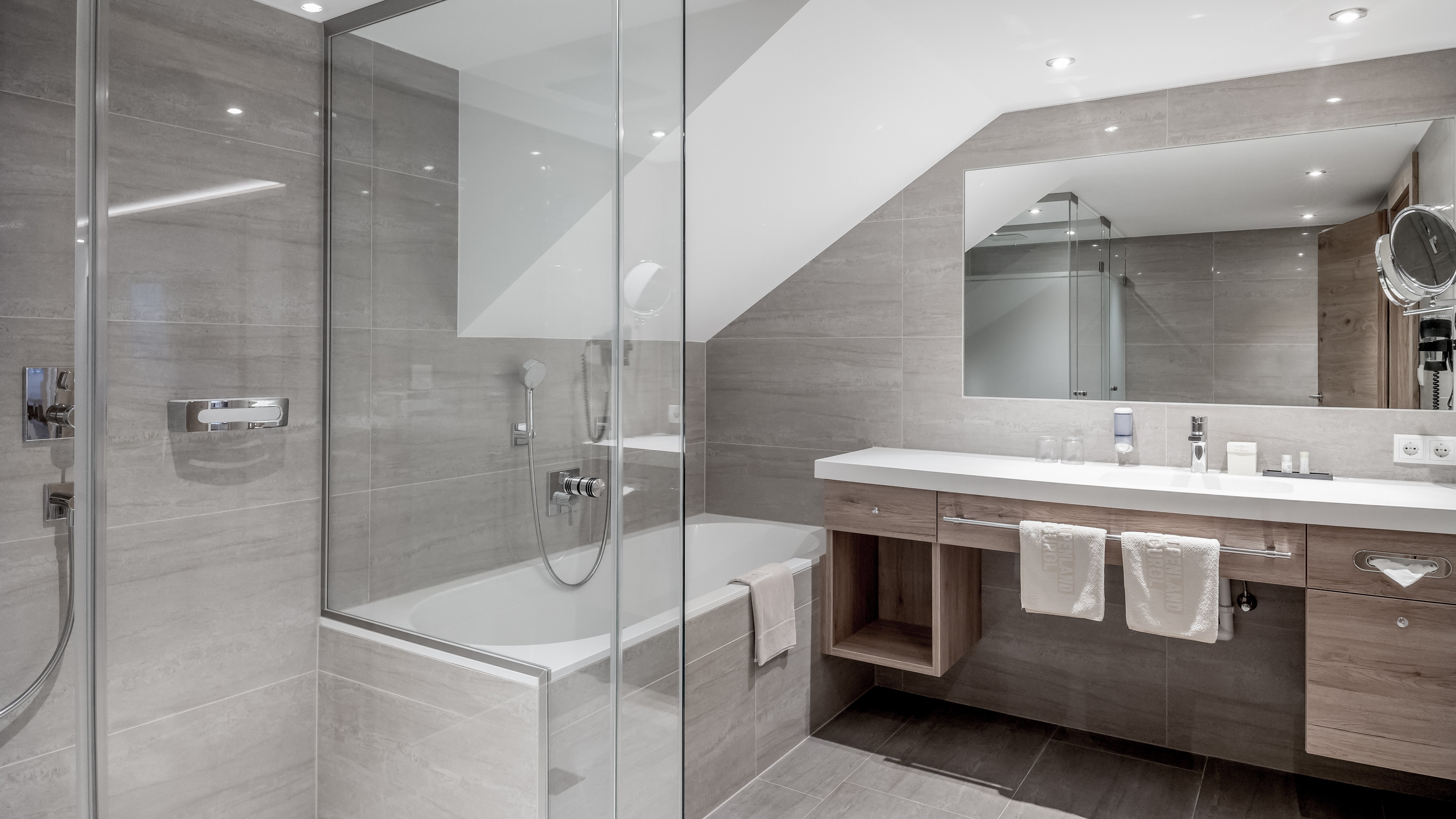 Modernes Badezimmer mit gläserner Duschabtrennung Badezimmer mit einer modernen Dusche, Badewanne und Spiegelkommode in neutralen Tönen.