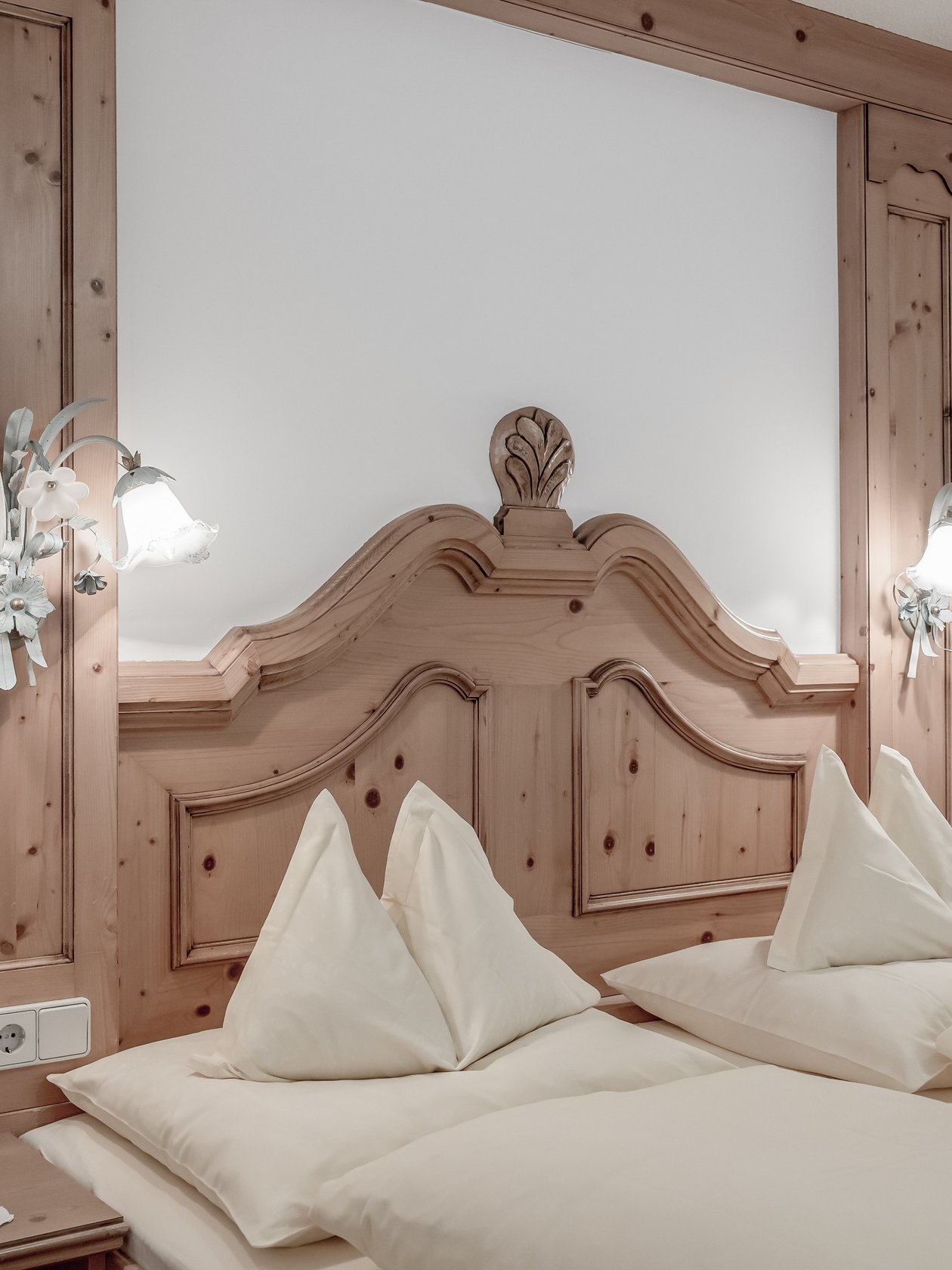 Helles Hotelzimmer mit zwei Betten und einem Holzkopfteil, weiße Bettwäsche und dekorative Elemente.
