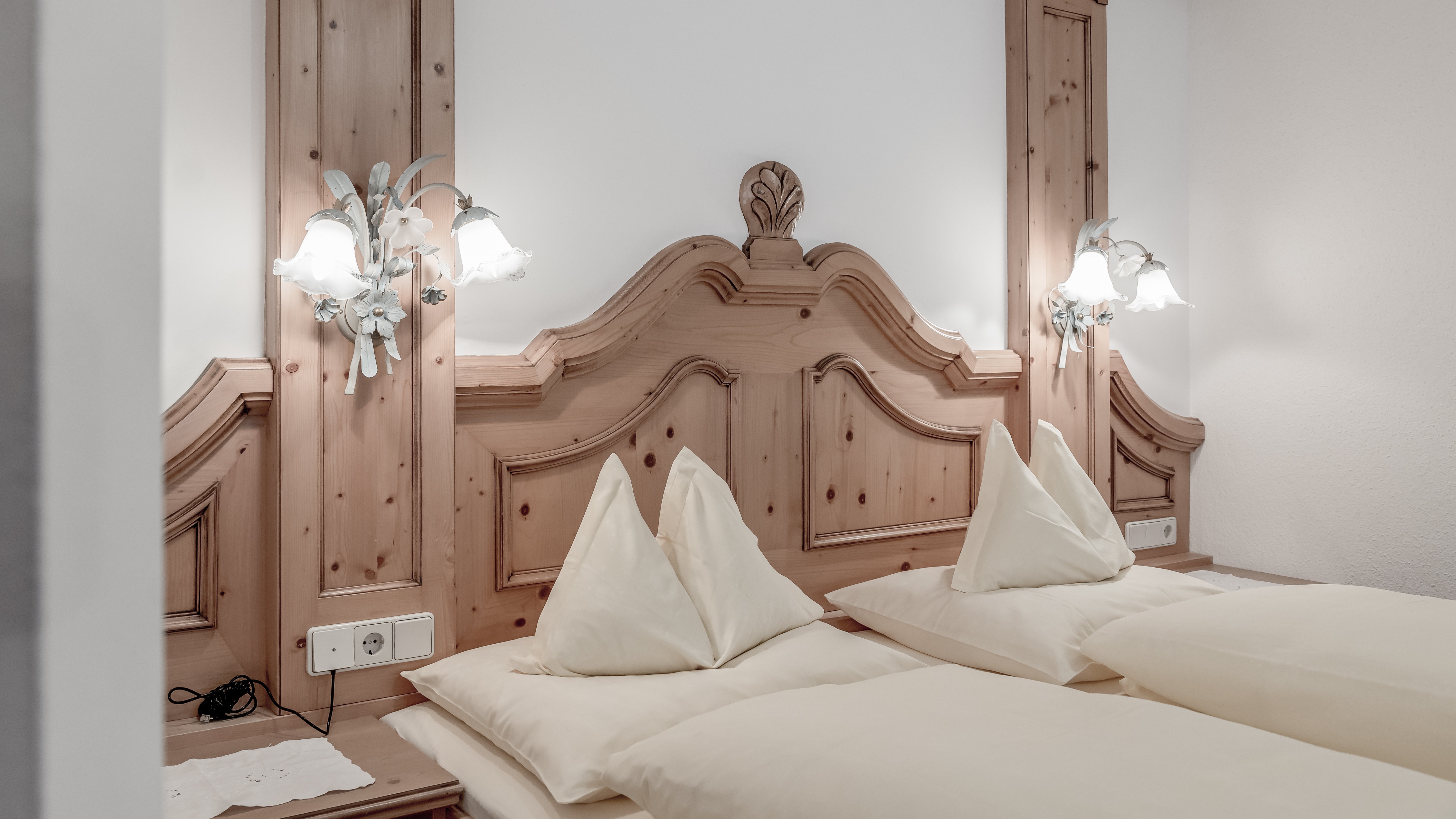 Komfortable Hotelzimmer in Holzdesign Helles Hotelzimmer mit zwei Betten und einem Holzkopfteil, weiße Bettwäsche und dekorative Elemente.