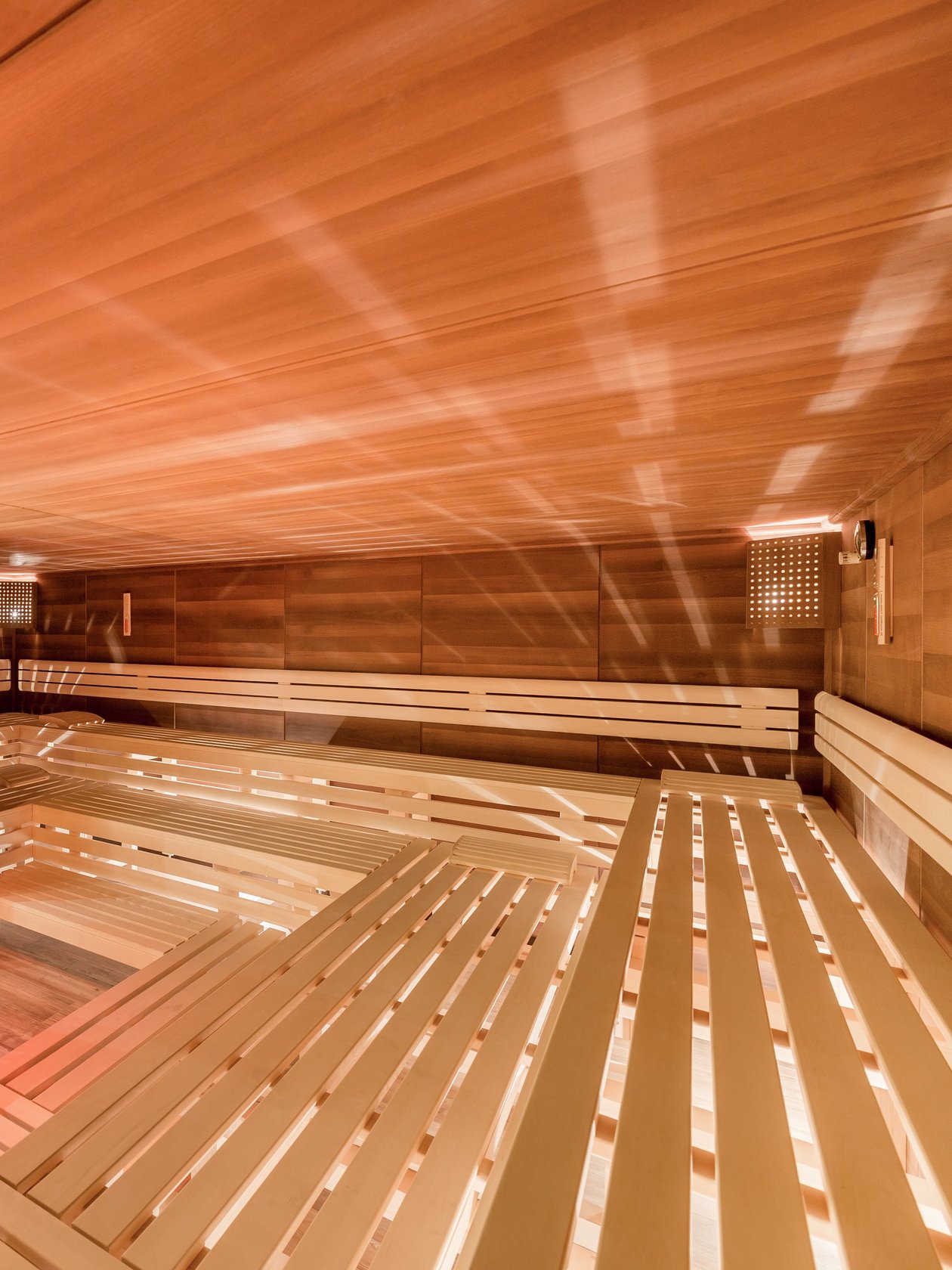 Interior der Sauna mit Holzbank und warmem Licht zur Entspannung gestaltet. Keine Personen sichtbar.