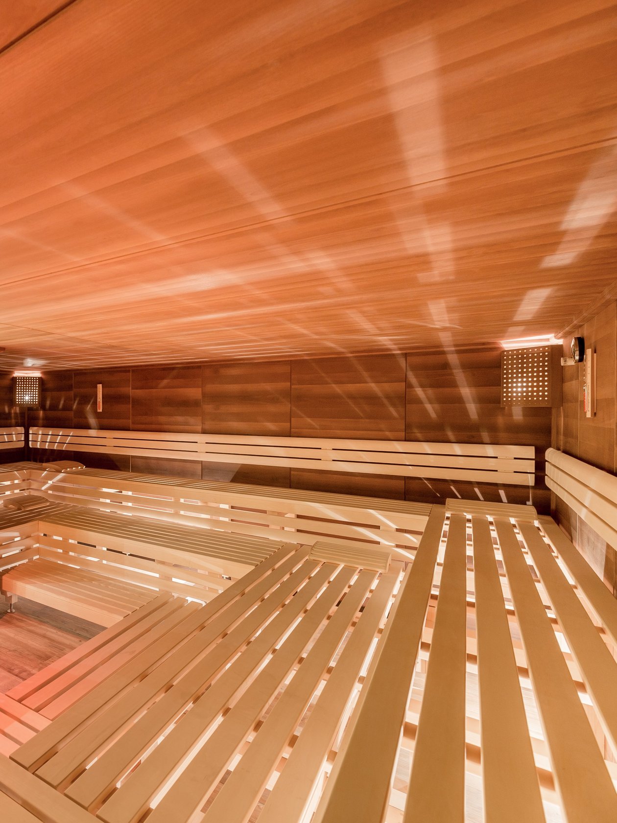 Interior der Sauna mit Holzbank und warmem Licht zur Entspannung gestaltet. Keine Personen sichtbar.